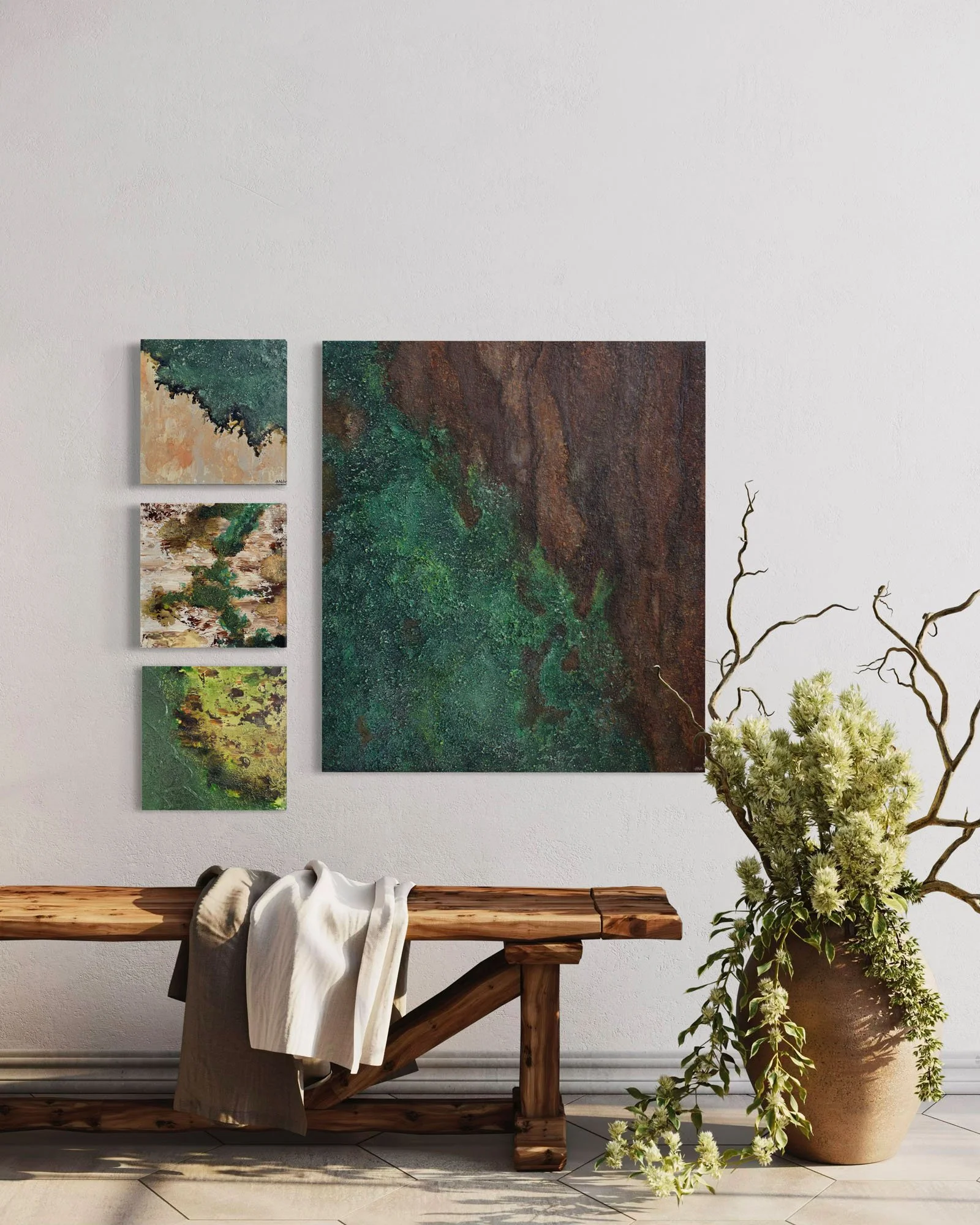 Interior decor featuring four abstract paintings on a white wall, a wooden bench with a white draped cloth, and a large beige pot with lush green and white flowers and branches.