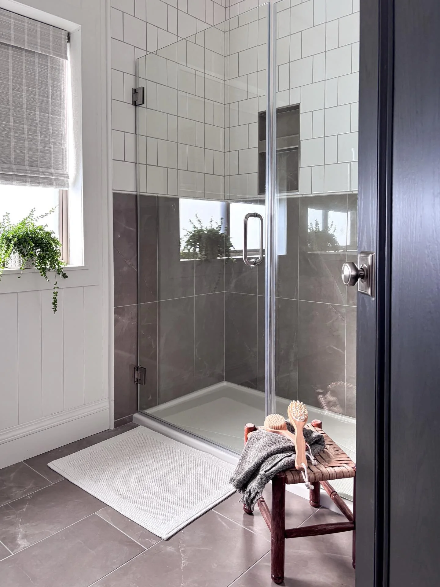 A primary bathroom should feel like a place you want to start and end your day.

Materials don&rsquo;t have to be complicated to create interest. Vertical shiplap and a bamboo window treatment add subtle texture, while the double vanity introduces wa