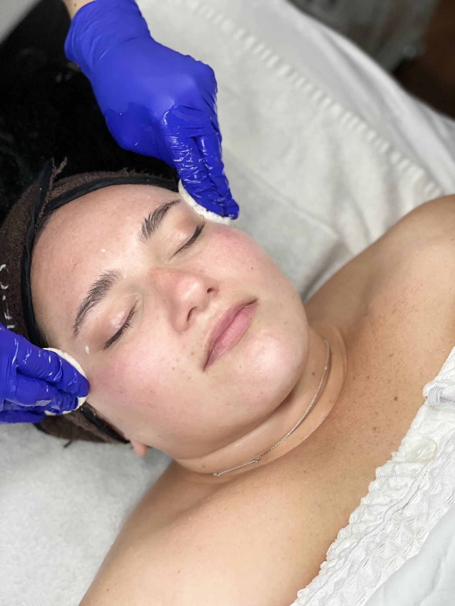 relaxed woman with her eyes closed receiving a facial