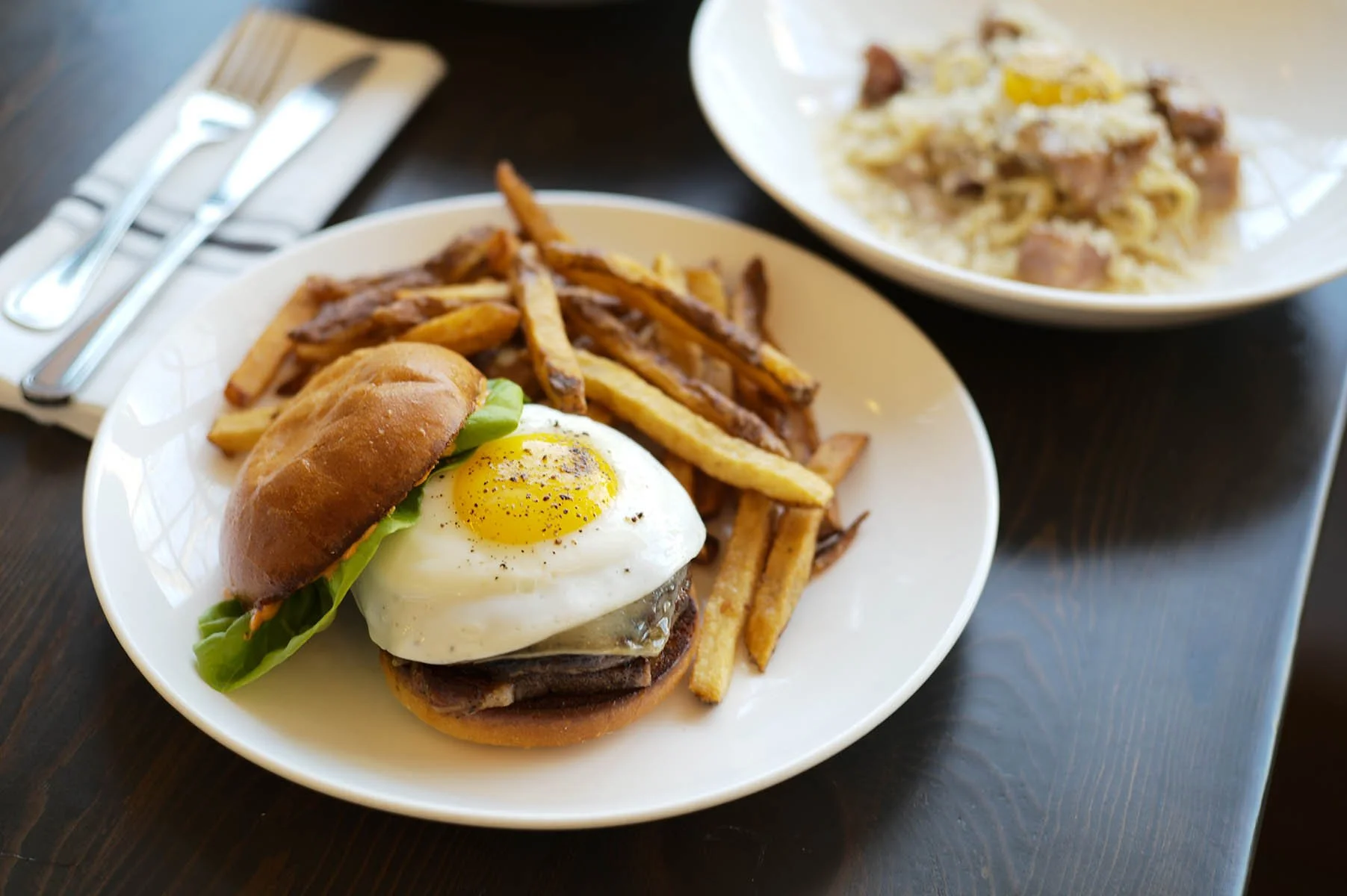 The Kenwood burger with sakura farms wagyu beef, tomato aioli, brioche bun, pork belly, gruyere, and a fried egg.