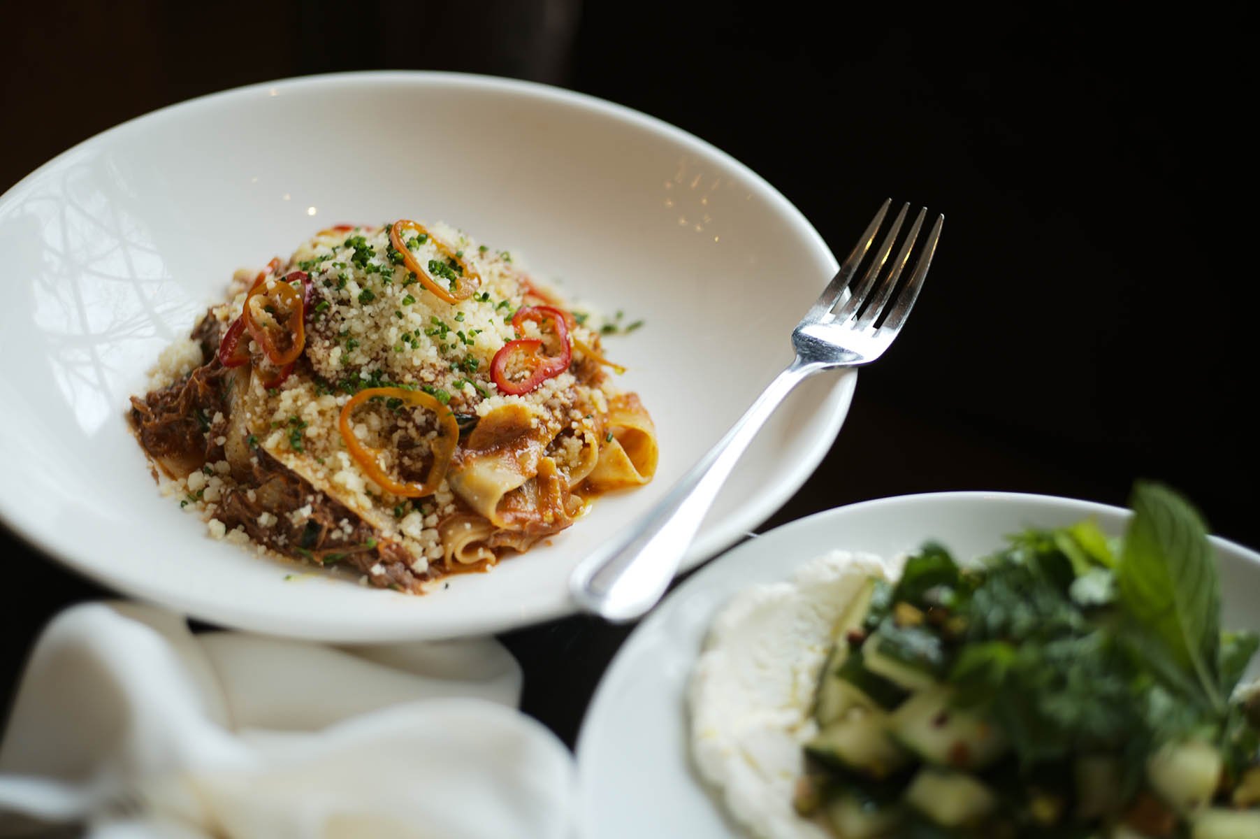Homemade lamb pappardelle pasta with marinated cucumbers over whipped ricotta.