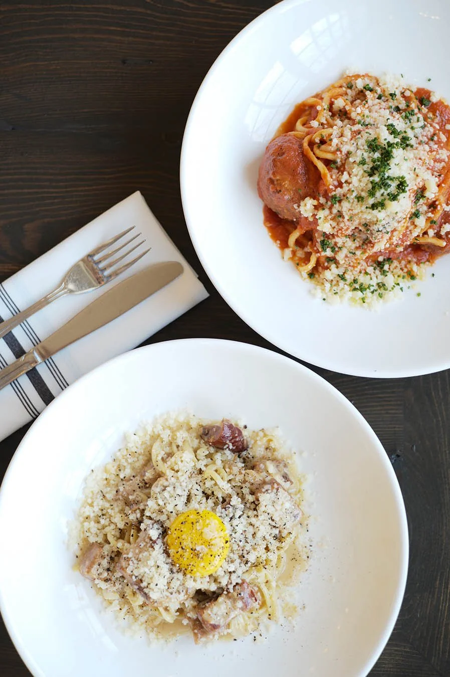 Two homemade pasta dishes including bucatini carbonara and spaghetti with meatballs.