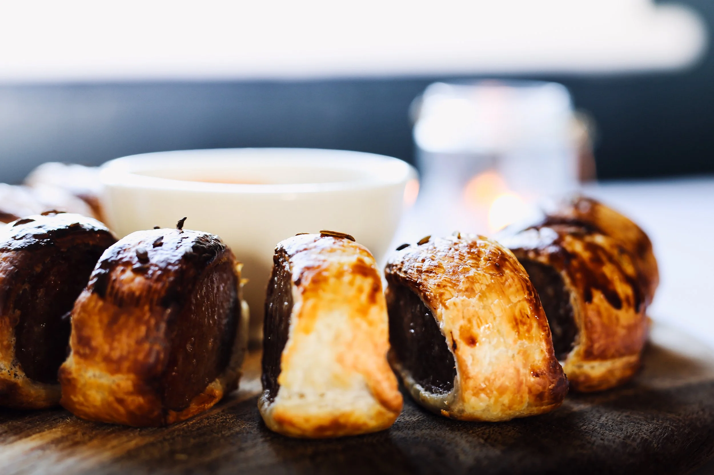 Close-up of chocolate croissants on a wooden surface with a white cup of coffee and a candle in the background at the Palace Hotel 