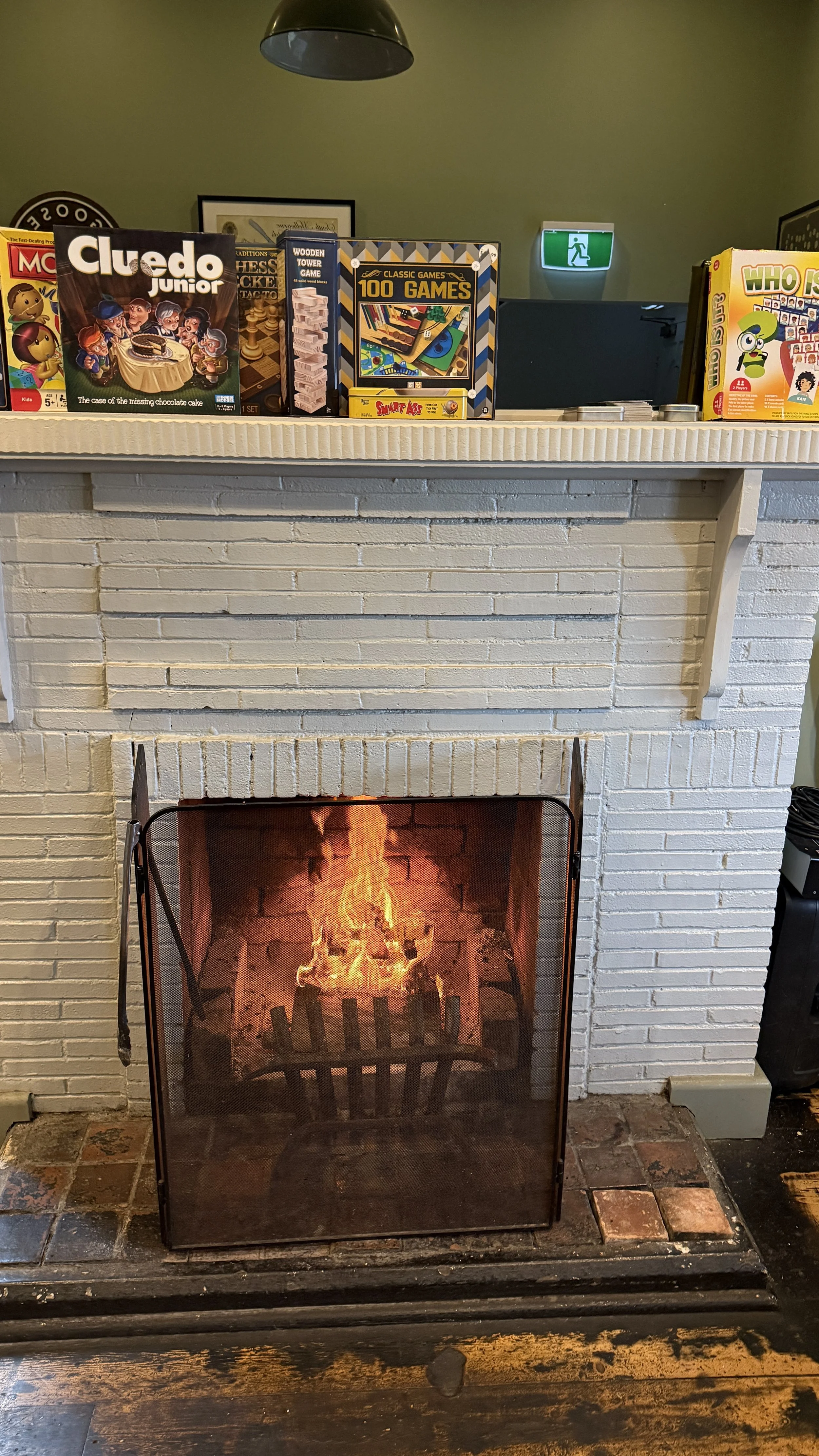 A hearty real fireplace with games on a shelf