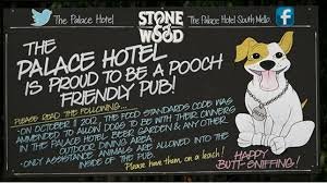 A chalkboard sign at The Palace Hotel promoting the pub's dog friendliness and stating it is a proud pooch pub, with a drawing of a dog and a happy birthday message.