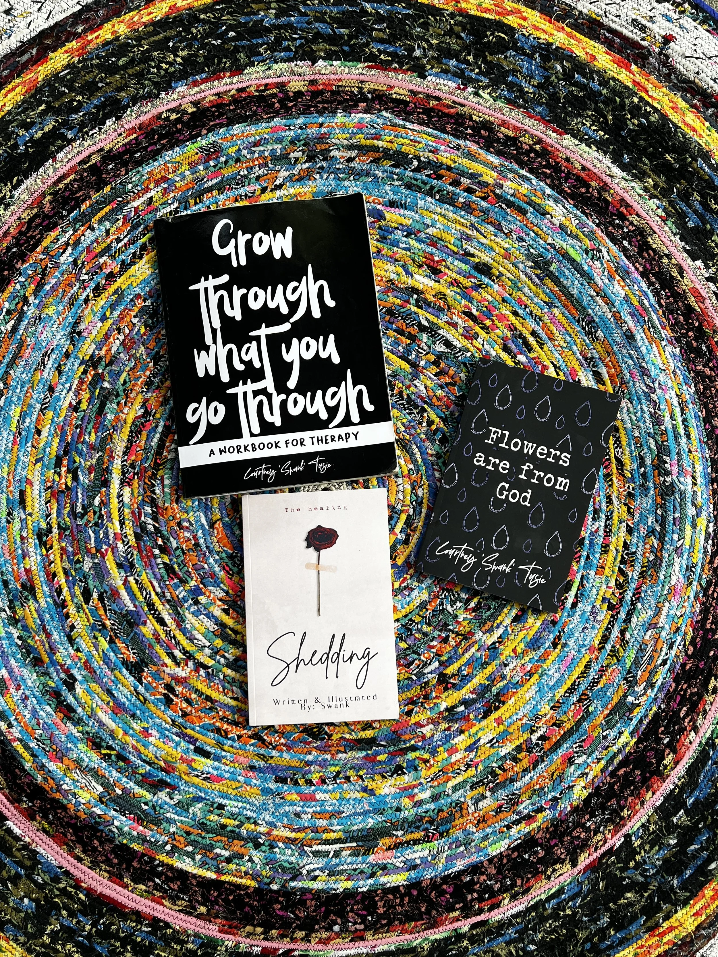 Books by Self Care Swank displayed on a colorful handmade rug.
