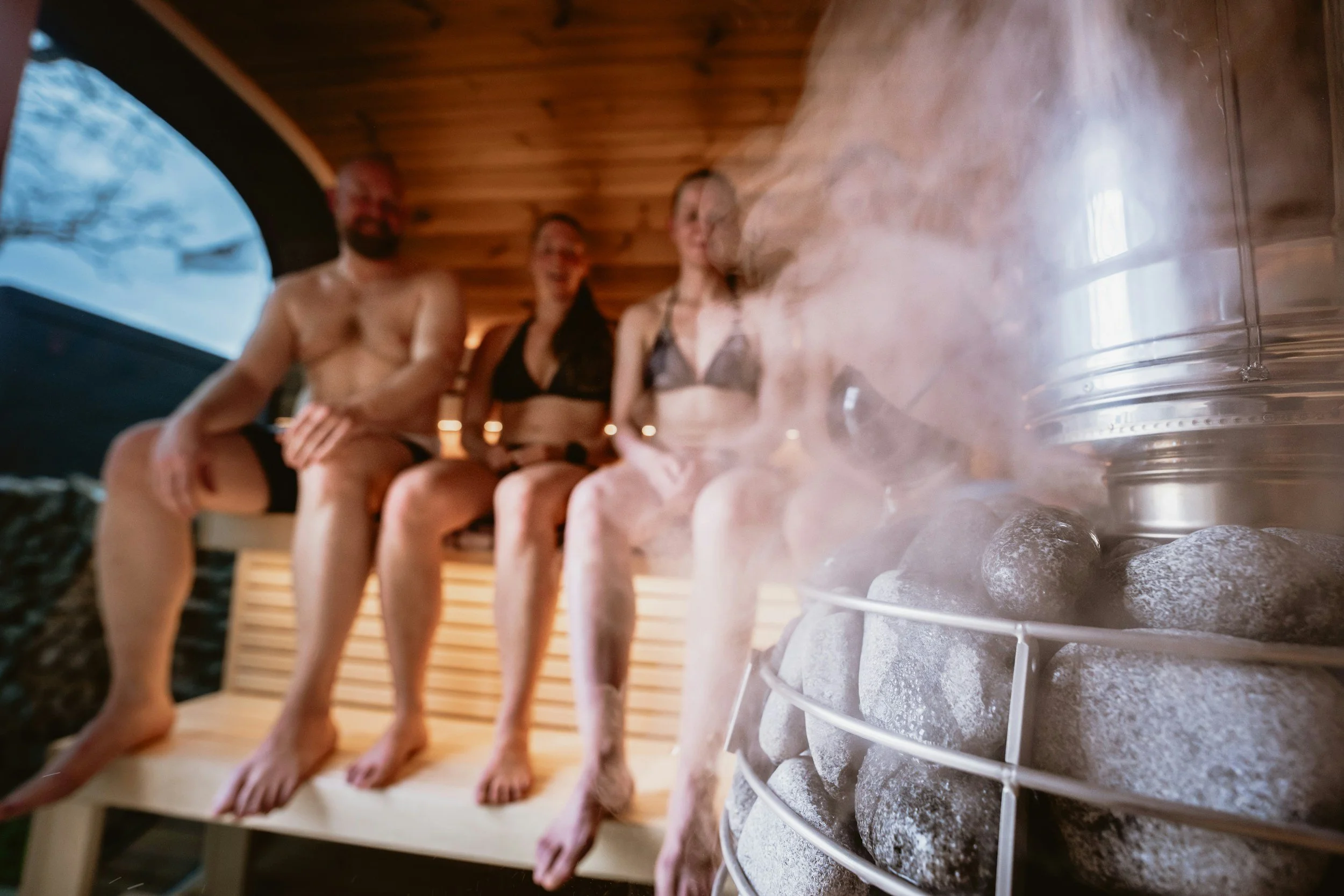 Group in a sauna with steam coming off the coals
