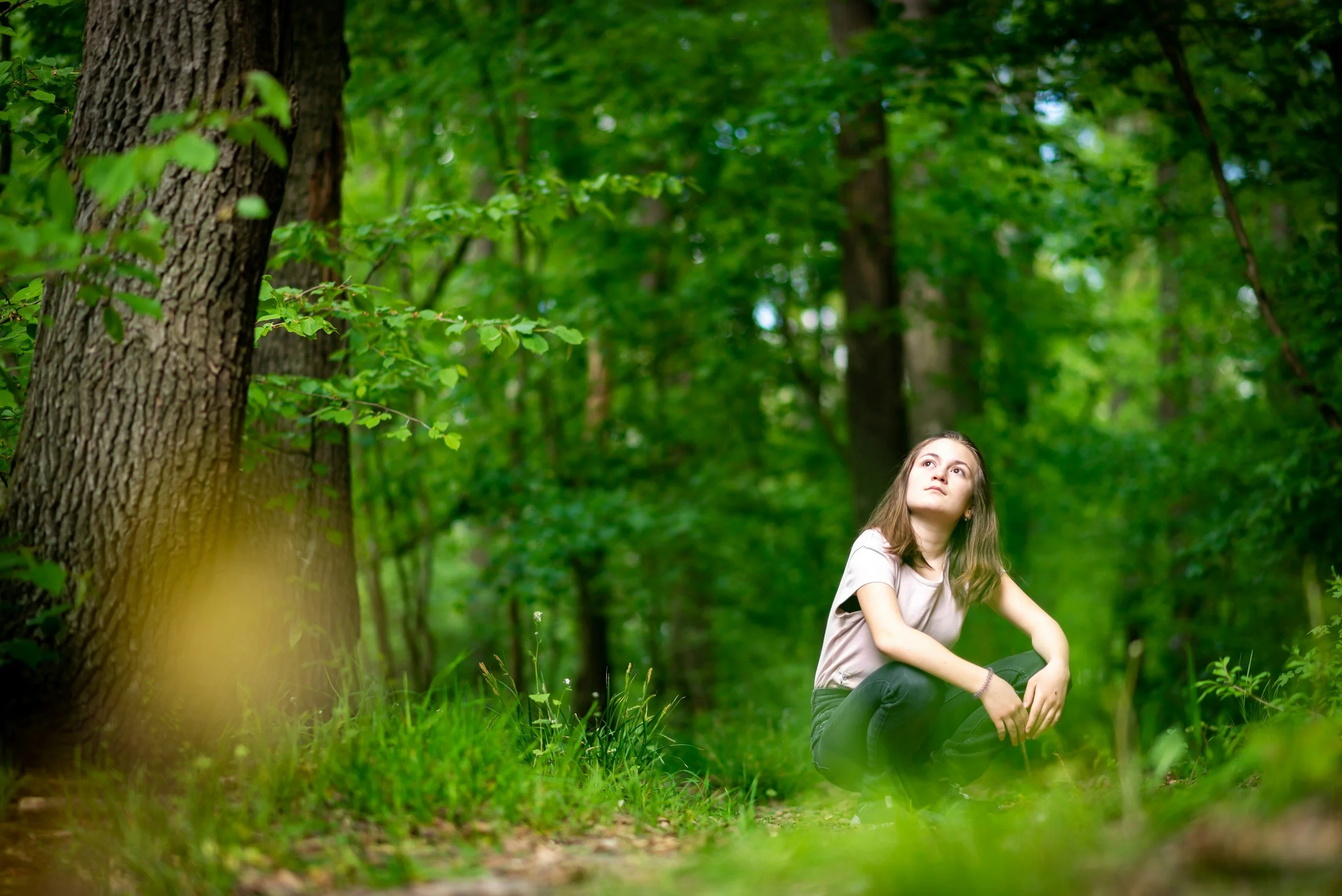 A woman sitting in woodland and listening mindfully