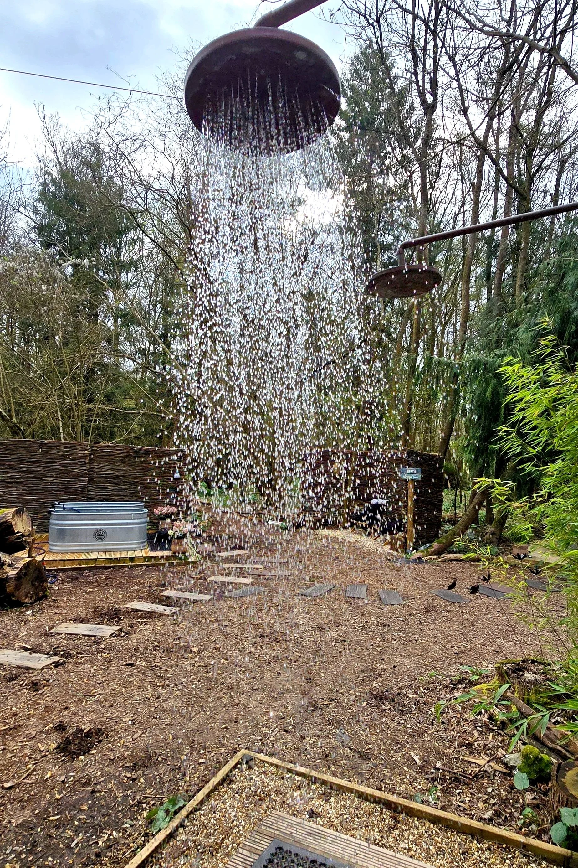 A cold shower on in a natural setting with cold tubs in the background