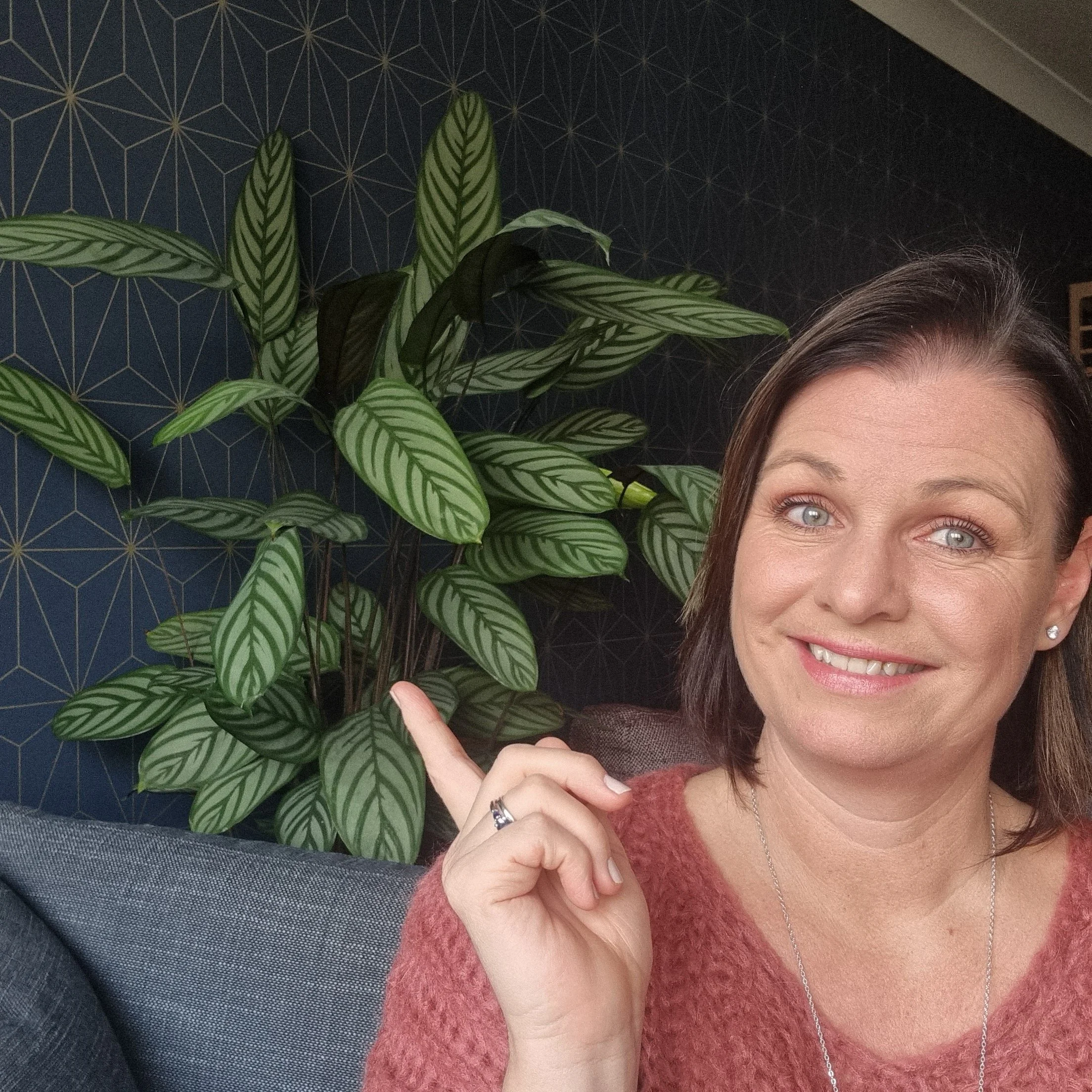 Chantelle sitting with one of her favourite house plants near a reading corner of the lounge