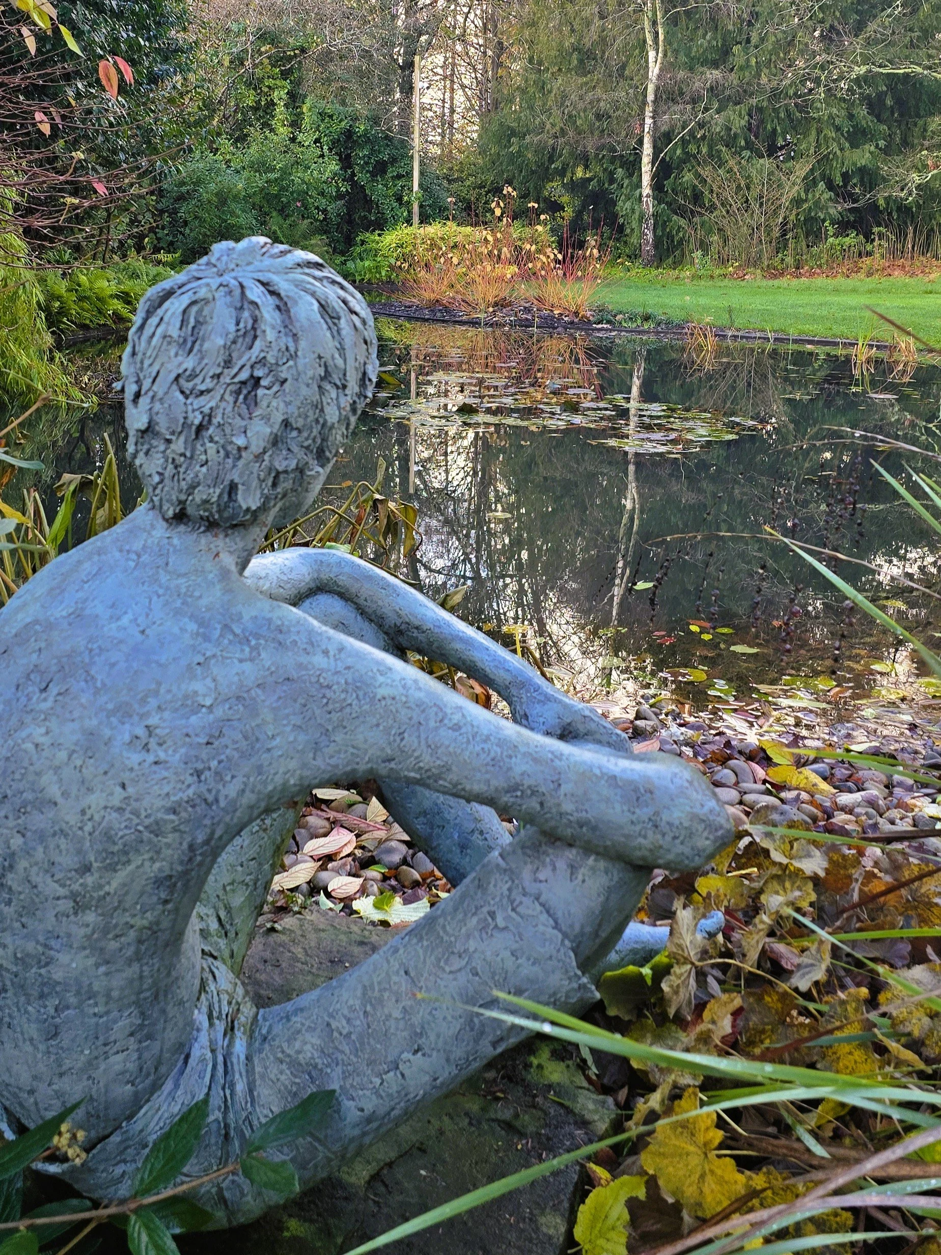 Statue looking out over a pond
