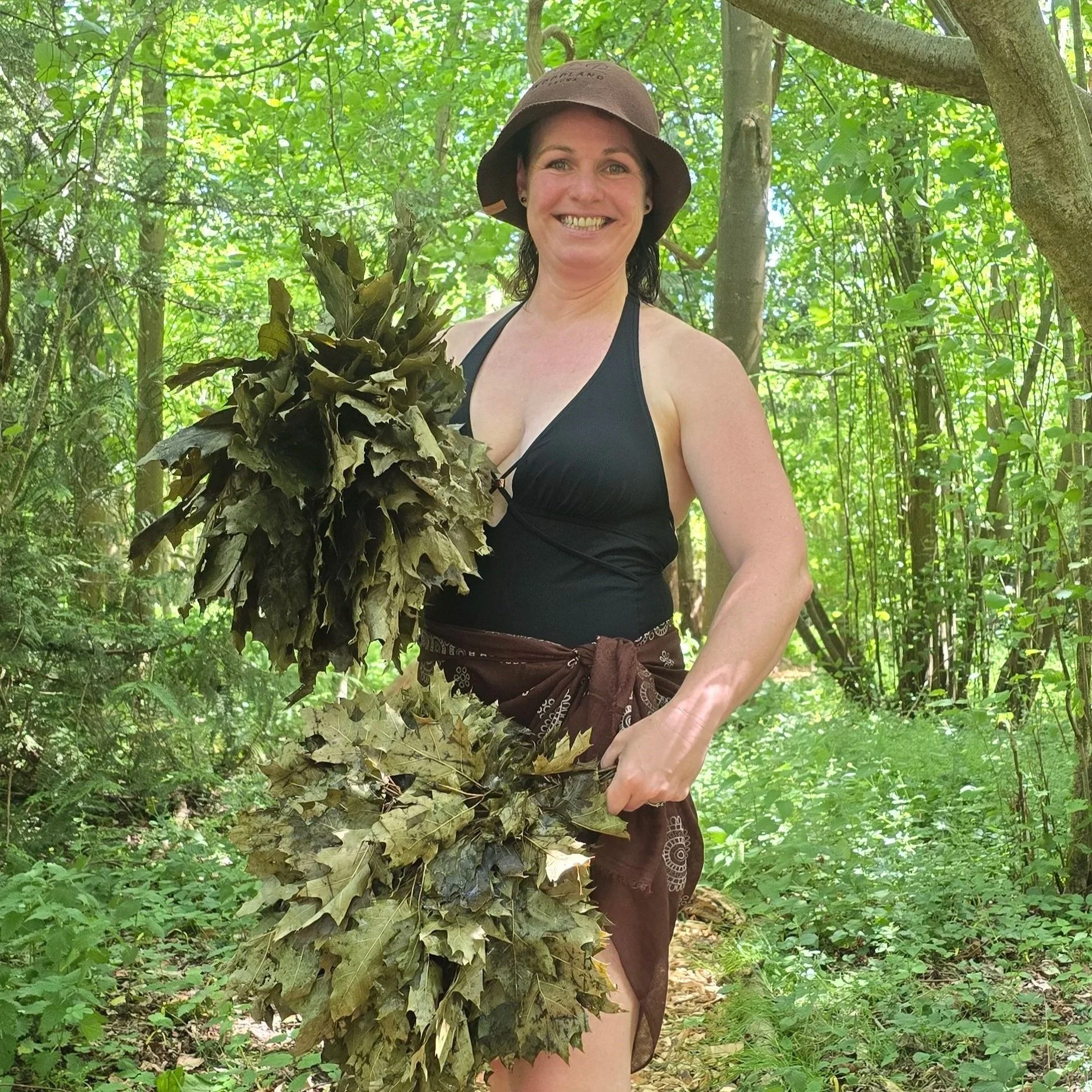 Sauna Master Chantelle in woodland holding 2 oak leaf whisks