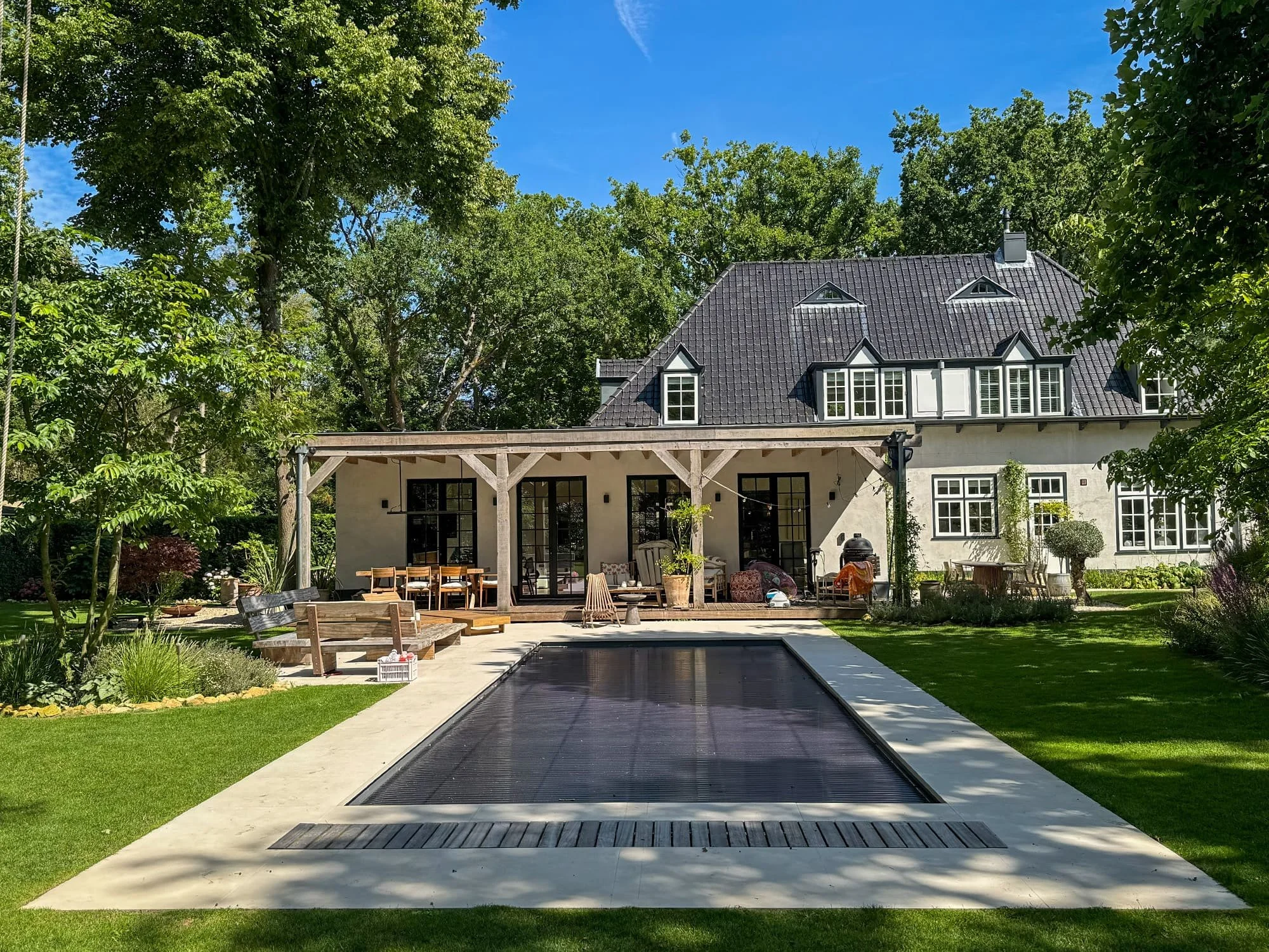 Voor deze villa in het bos hebben wij een strak tuinontwerp gerealiseerd. Het nieuwe, donkere zwembad sluit naadloos aan op de architectuur van de woning en wordt op natuurlijke wijze omlijst door de bestaande bomenrijen.