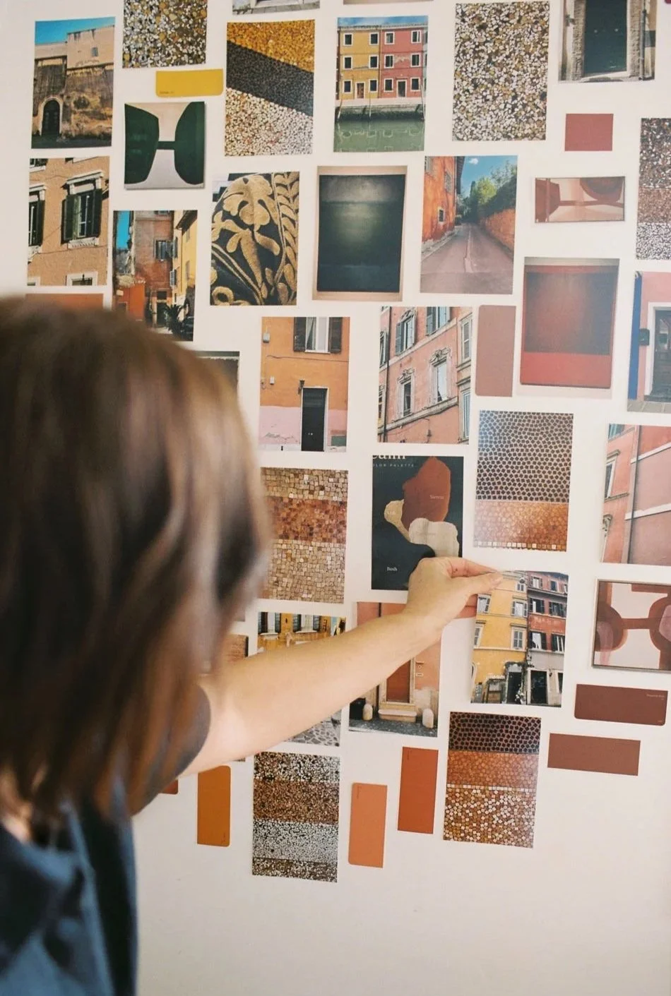 artist looking at colour palette images and photographs on a wall.