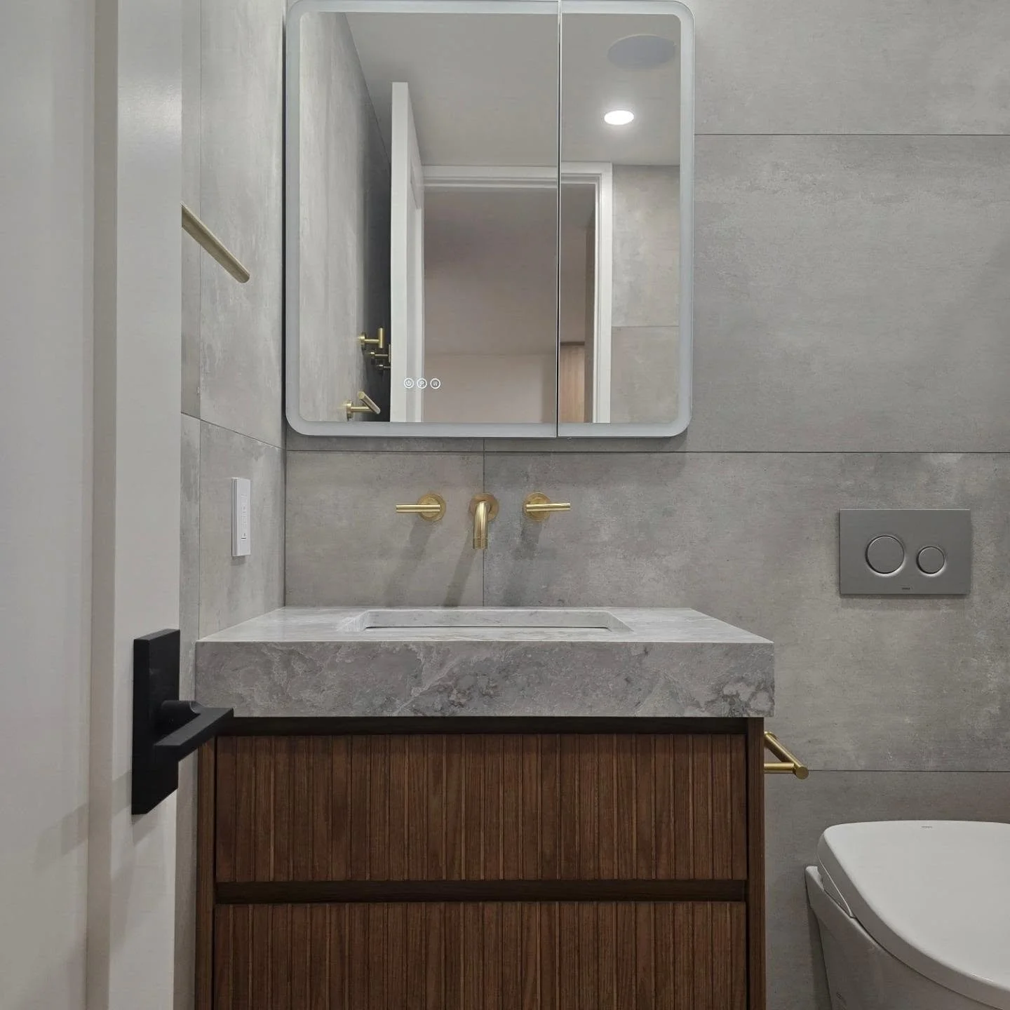 The vision was to create a serene, spa-like sanctuary that balances bold, modern lines with warm, inviting textures. Pairing large-format concrete-inspired tiles with a rich fluted walnut vanity and brushed gold fixtures brought the perfect harmony o