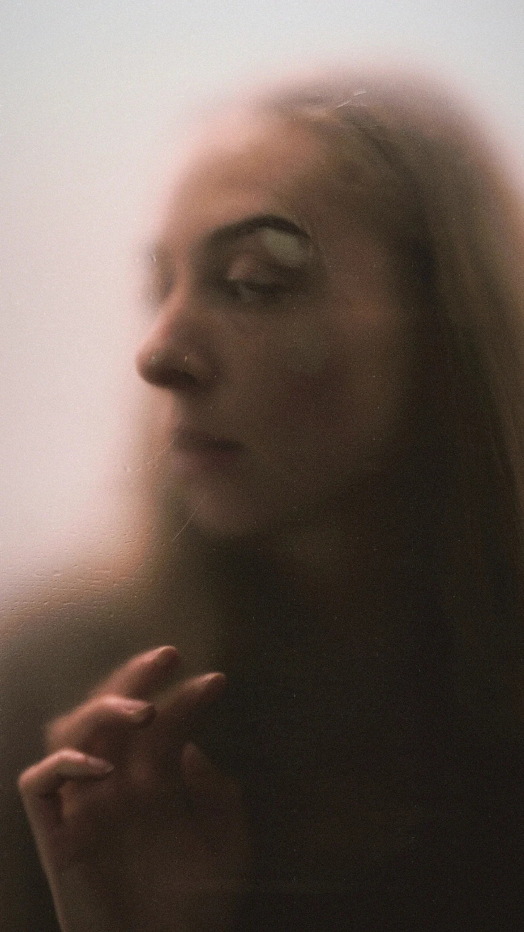 Portret achter matglas: vrouw in zacht, wazig licht