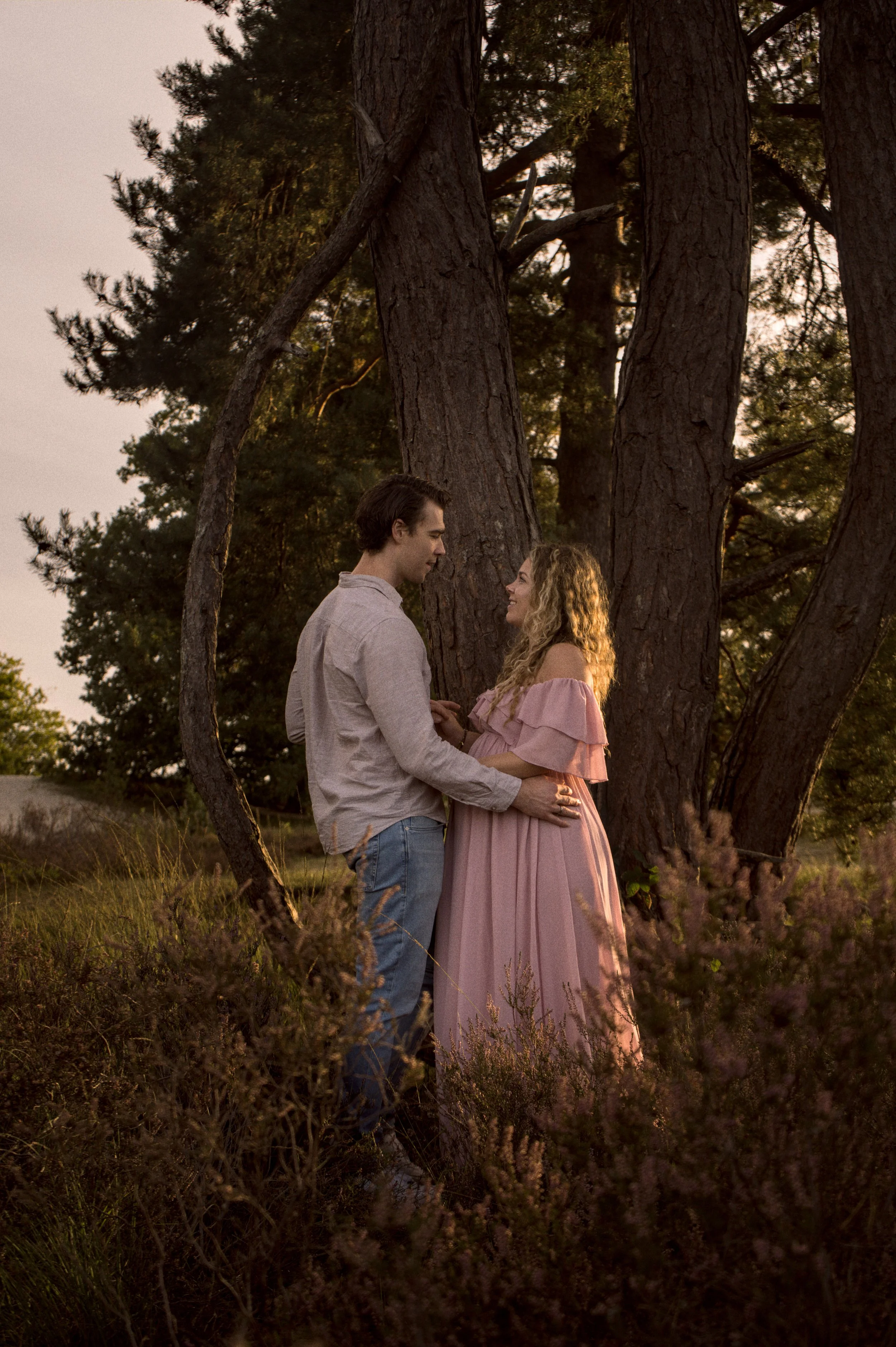 Zwangerschapsfotografie: aanstaande ouders in elkaars armen bij een boom op de heide