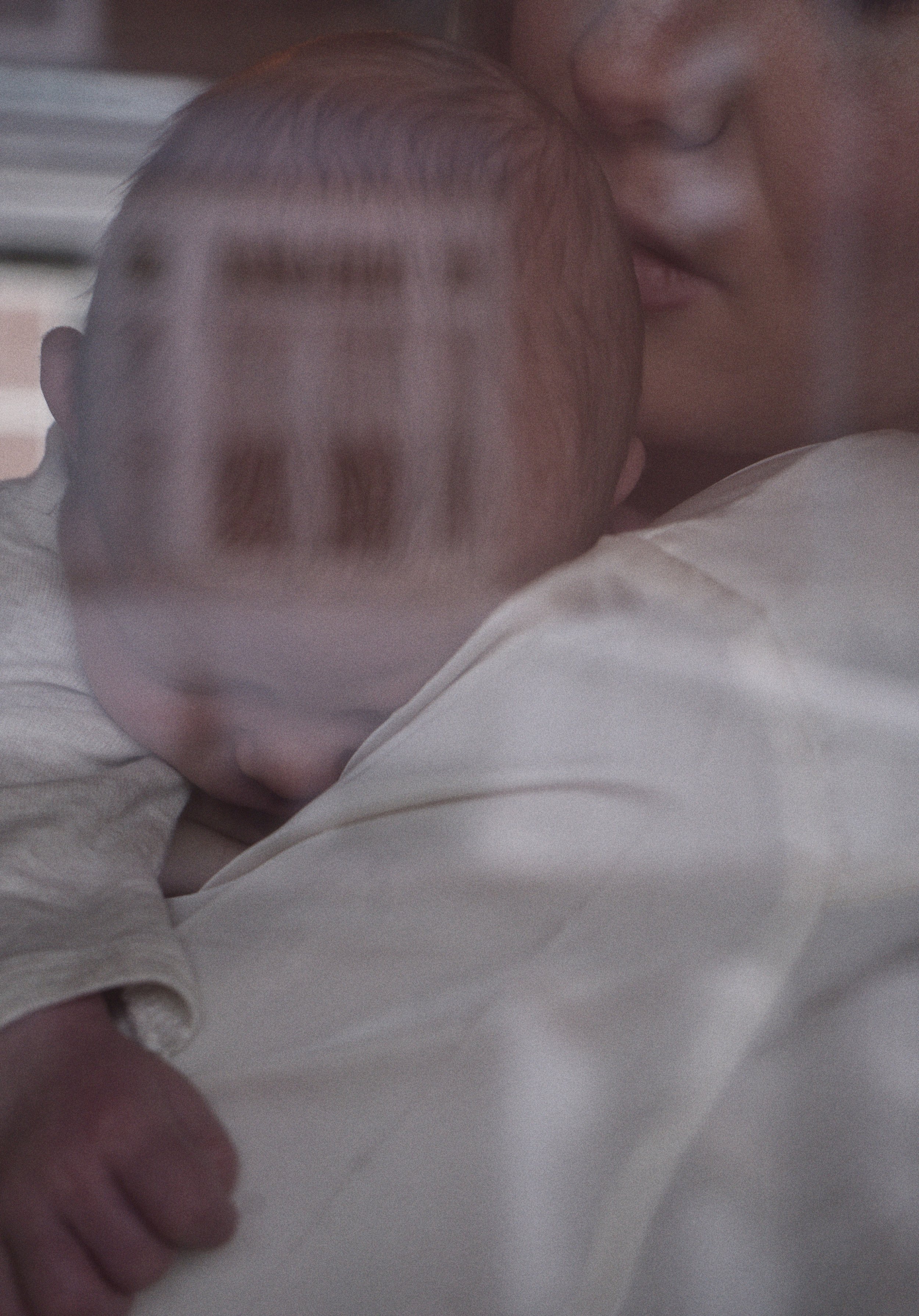 Newbornfotografie: een omhelzing gezien door een raam met weerspiegeling