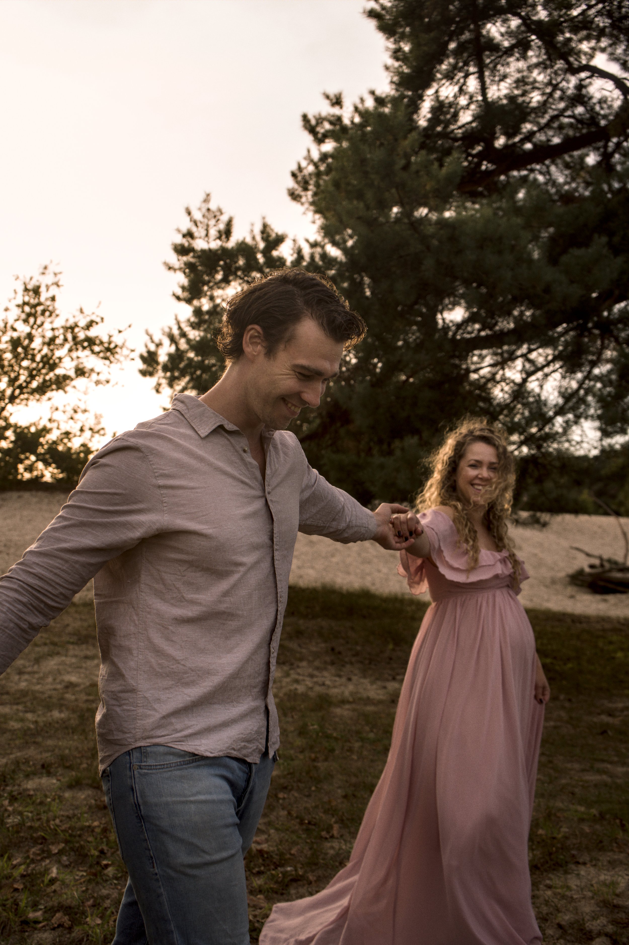 Zwangerschapsfotografie: lachend stel hand in hand op de heide
