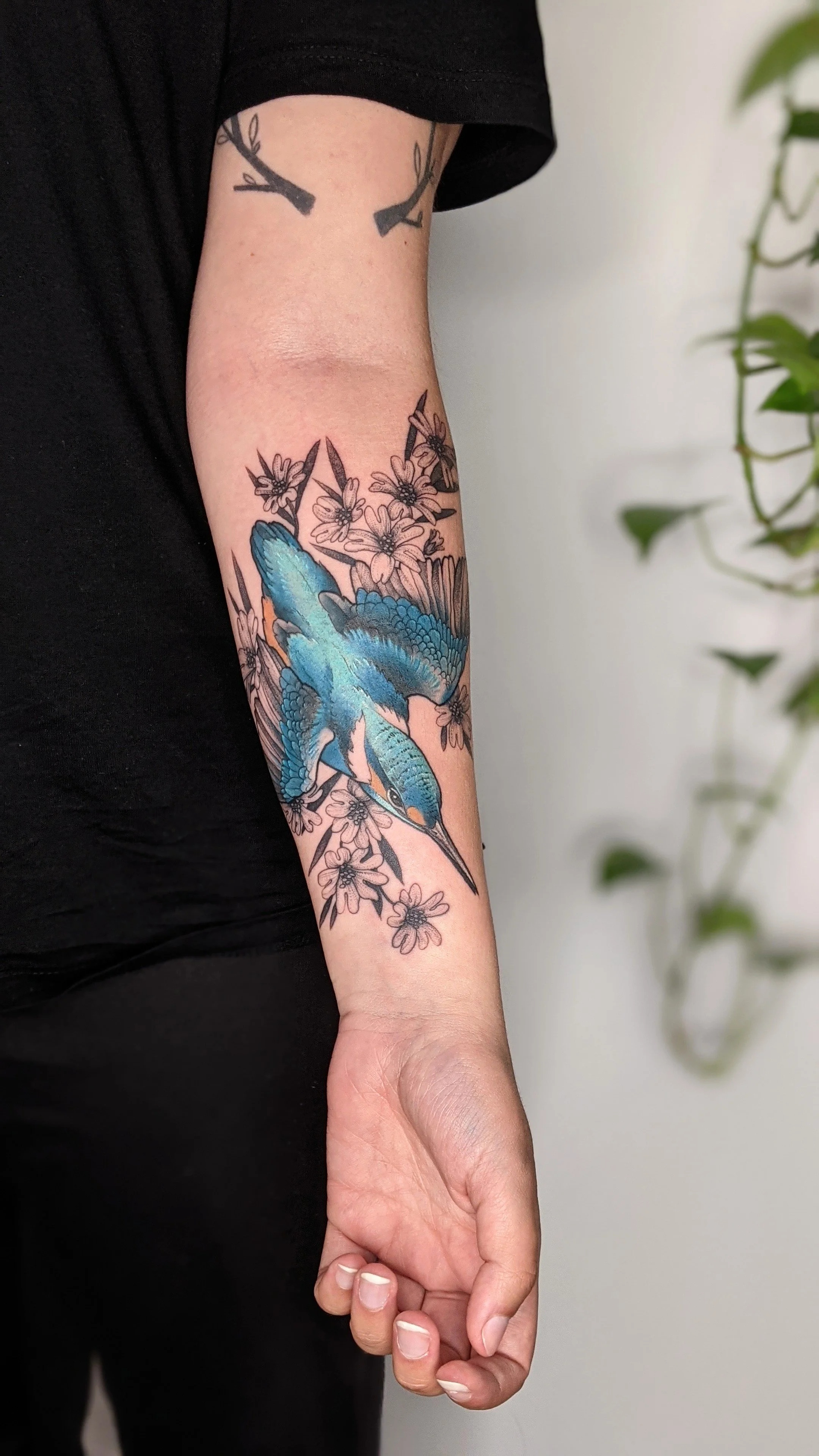 tatouage de martin pêcheur en couleurs avec des fleurs sur un bras.jpg
