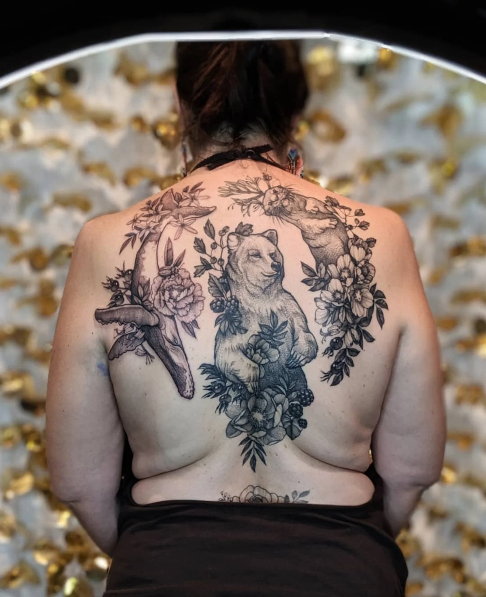 tatouage d'ours de baleine et de loutre avec du feuillage sur un dos.jpg