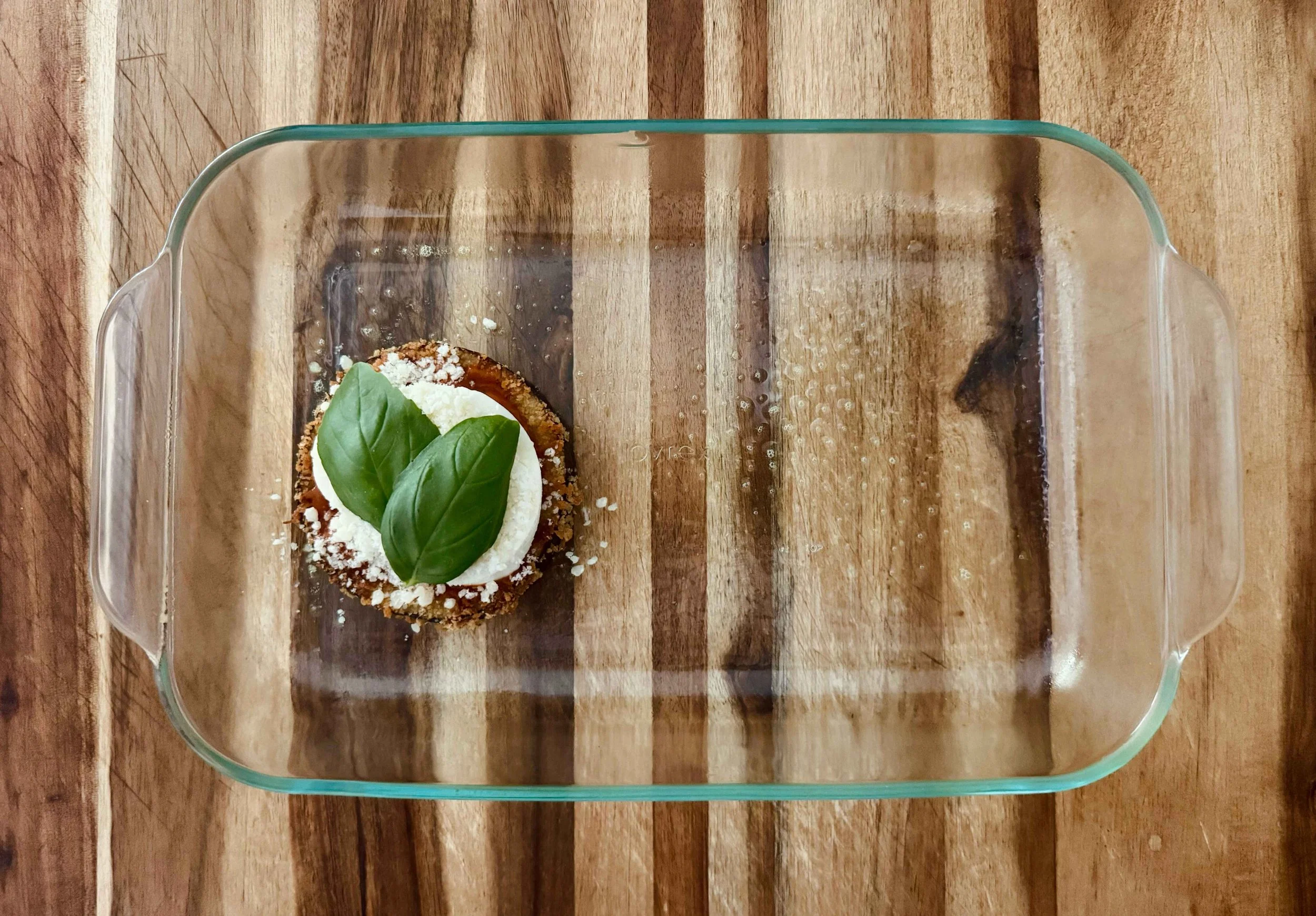 Photo of 2 basil leaves being added to eggplant stack