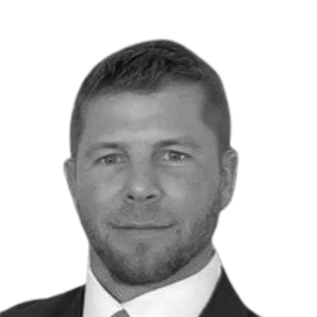 Black and white headshot of a man in a suit and tie with short hair, looking at the camera.