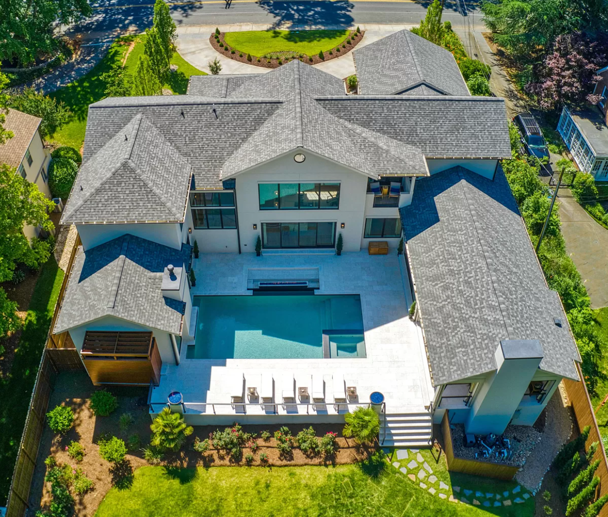 Aerial view of a modern house with a swimming pool in the backyard, surrounded by a landscaped garden and neighboring houses.