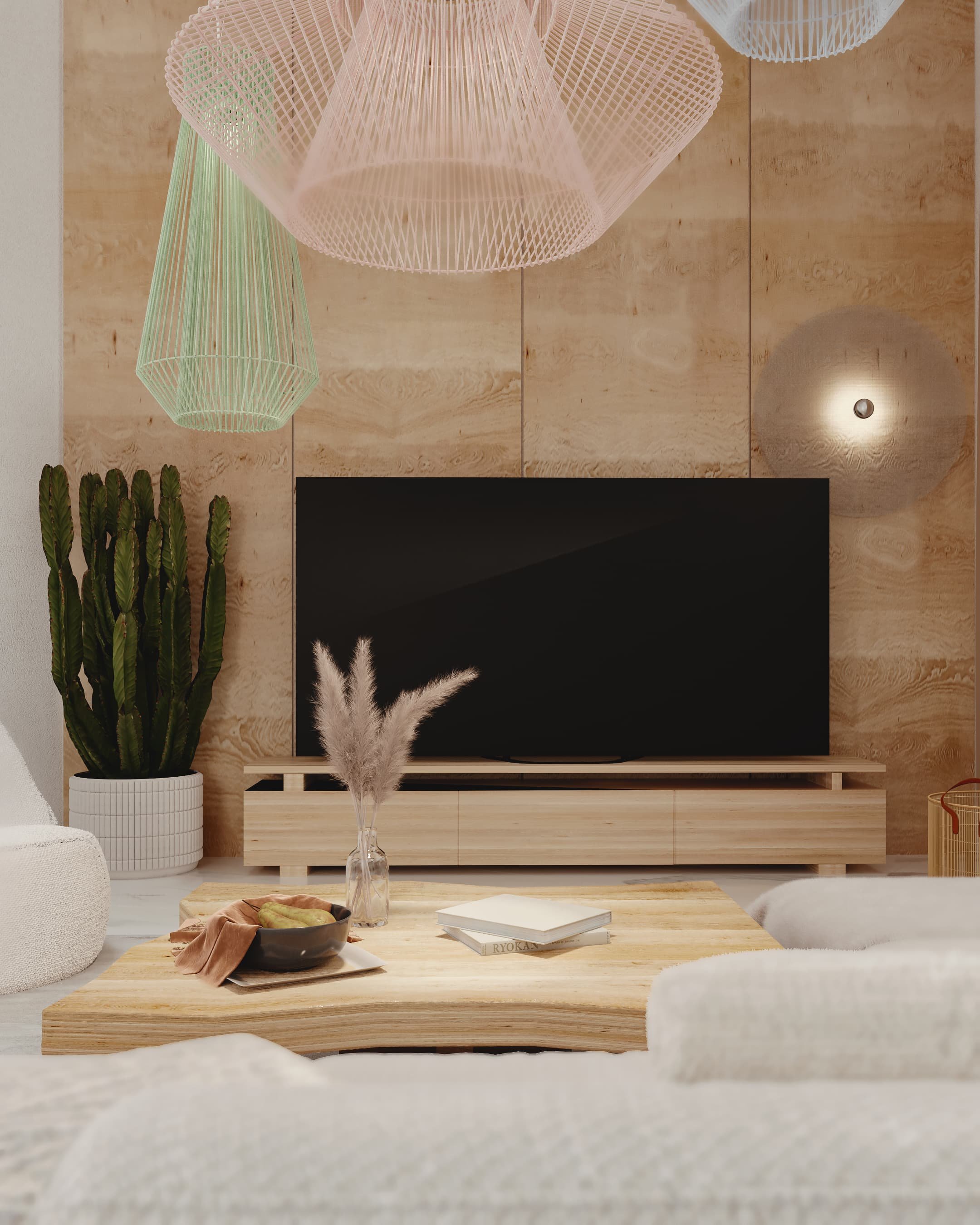 Modern living room with a wooden TV stand, flat-screen TV, a potted cactus, a glass vase with pampas grass, a bowl of snacks, and light-colored furniture and decor.