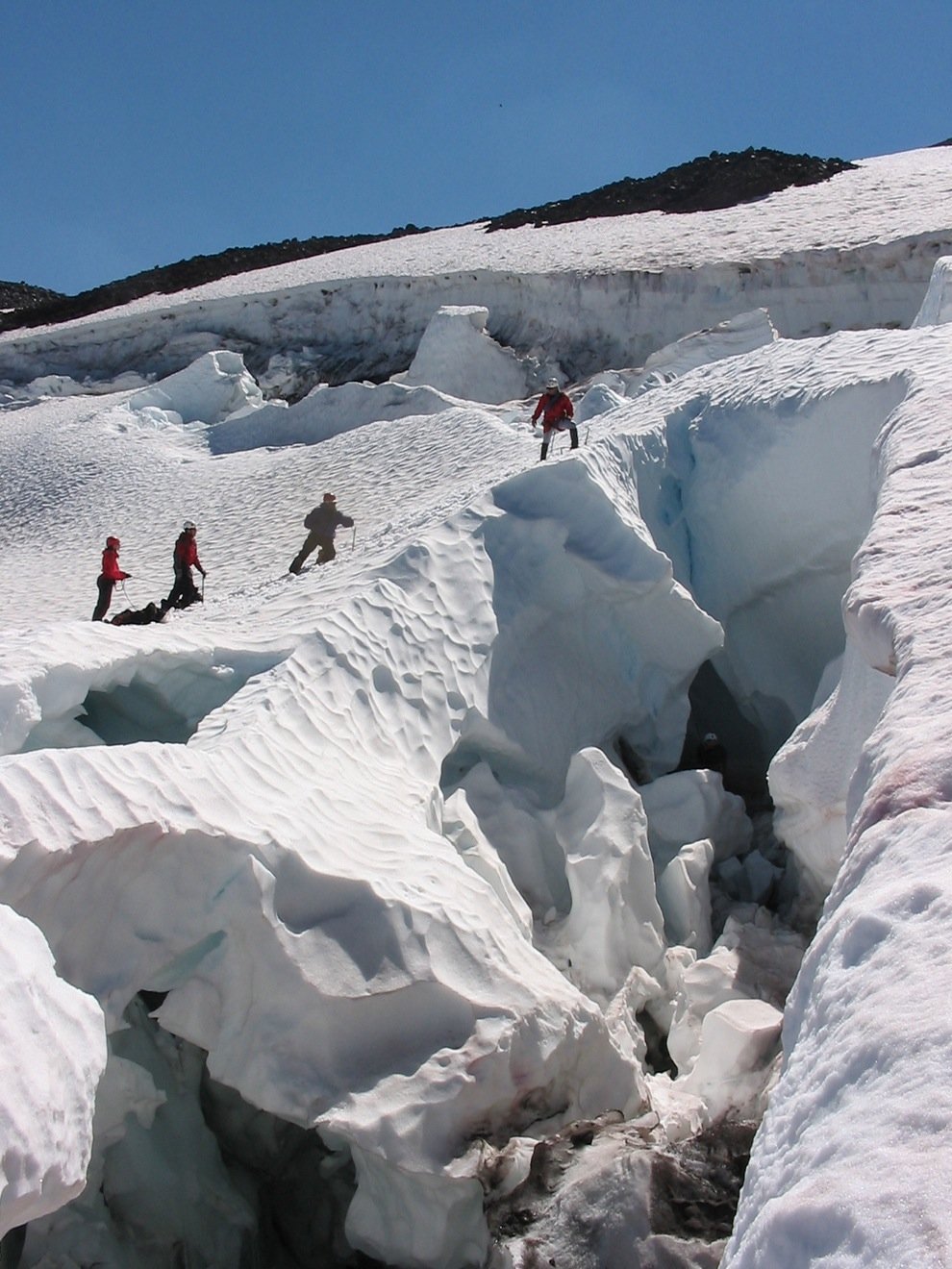 Mountaineers cross a crevasse on a mt shasta glacier 