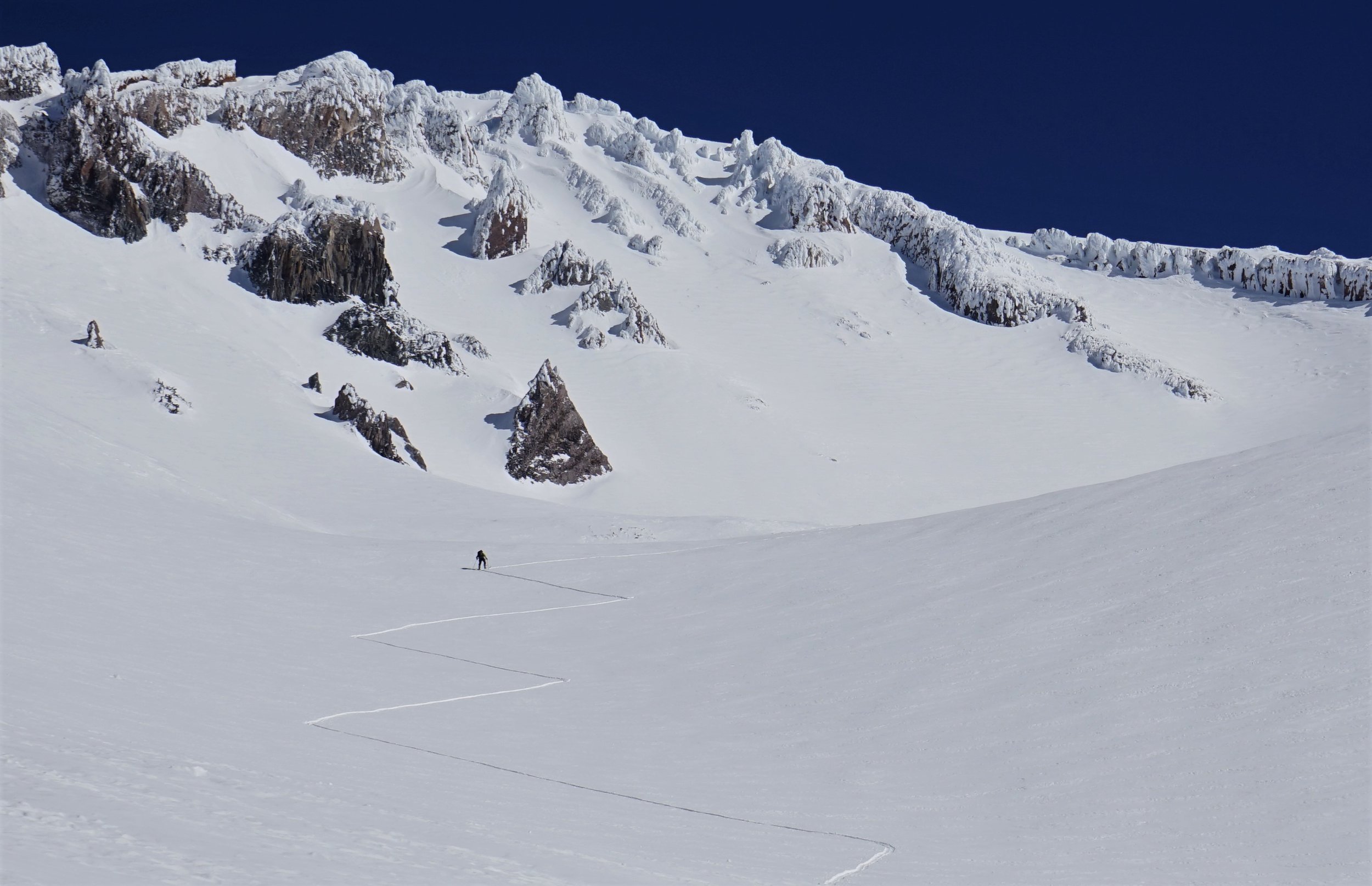 Skier skins up in a methodical zig zag up mt shasta
