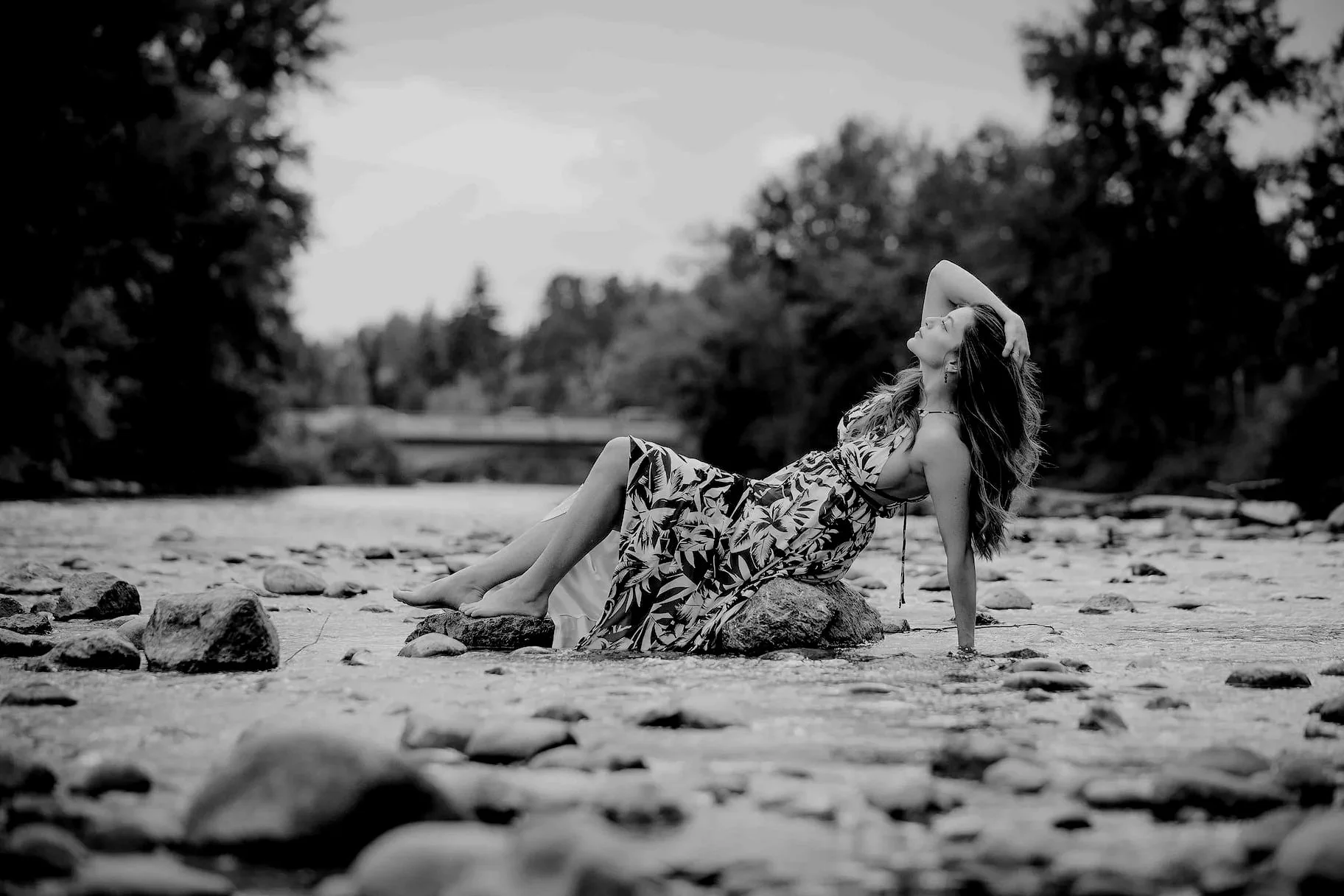 Model portrait photo of a woman sitting on a rock in Elbow River in Calgary during the summer time