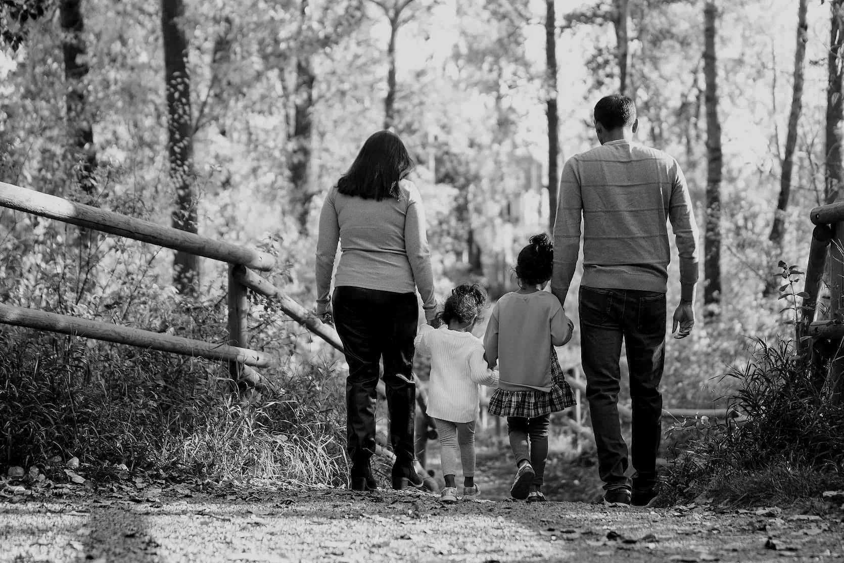 Family portrait photo of a family holding hands walking down a trail at Lindsay Park in Calgary during fall time