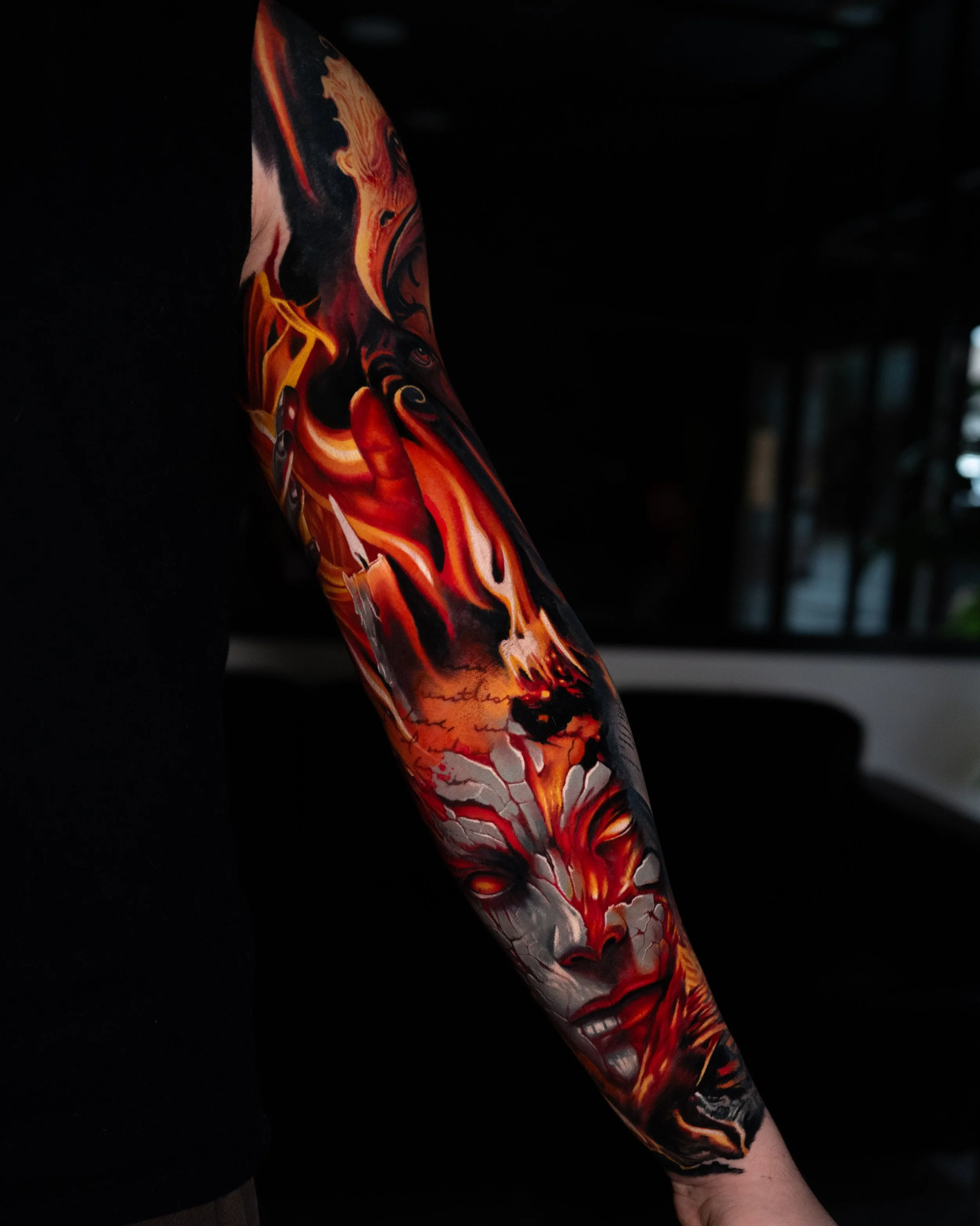 Colorful tattoo arm featuring a woman's face with flames and abstract designs.
