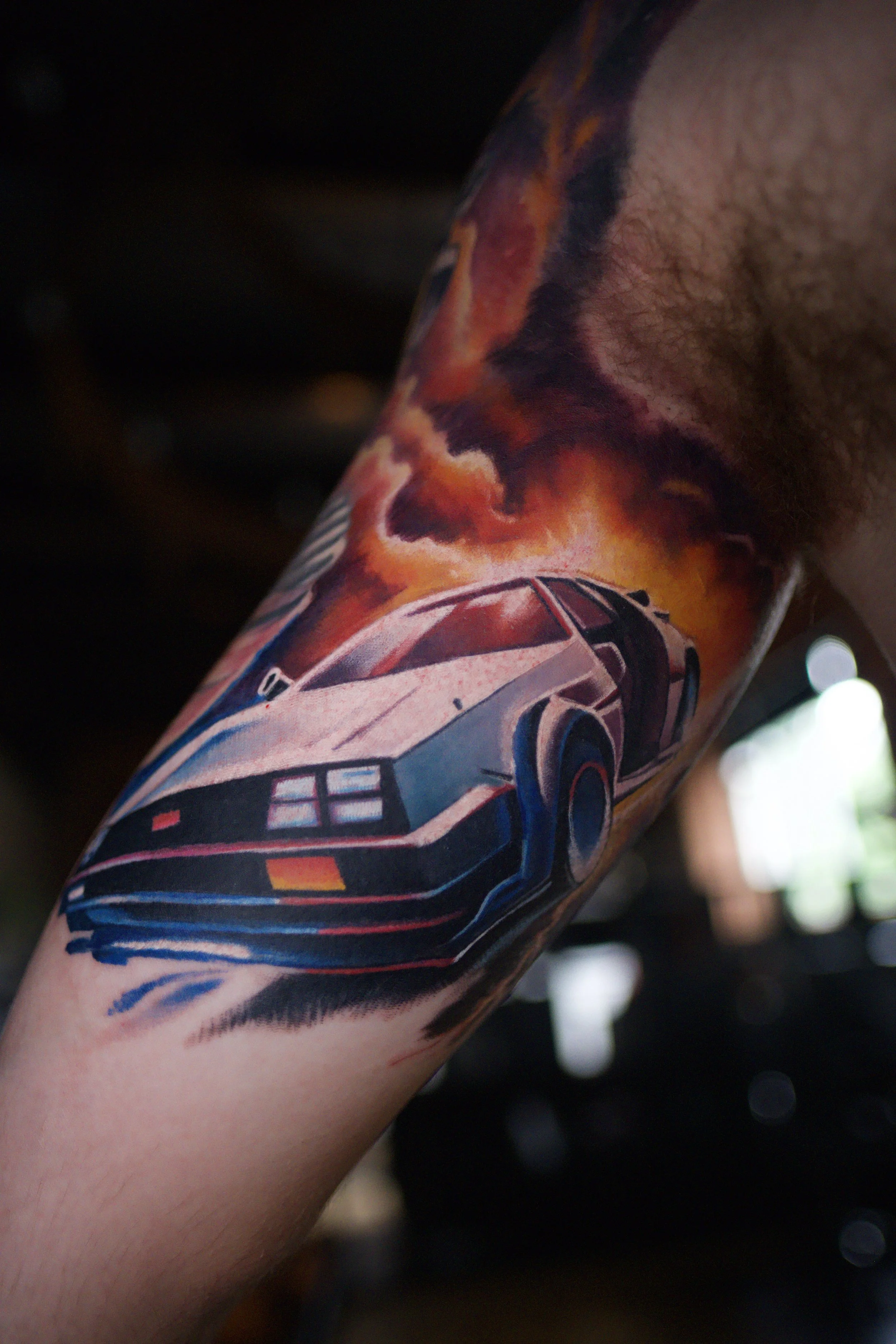 Tattoo of a DeLorean car with flames and smoke background.