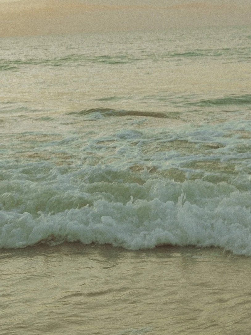 Waves crashing on a sandy beach at sunset or sunrise.
