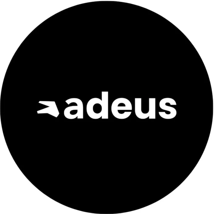 A black circular logo with the white text '> adeus' in the center.