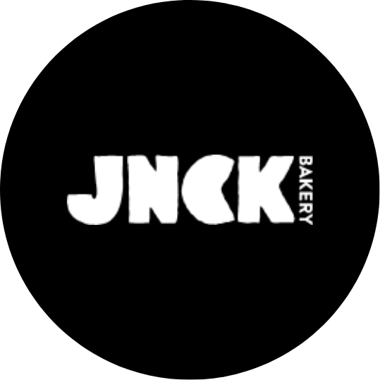 Logo with the text 'JNCK' and 'Bakery' written vertically to the right of 'JNCK', on a black circular background.