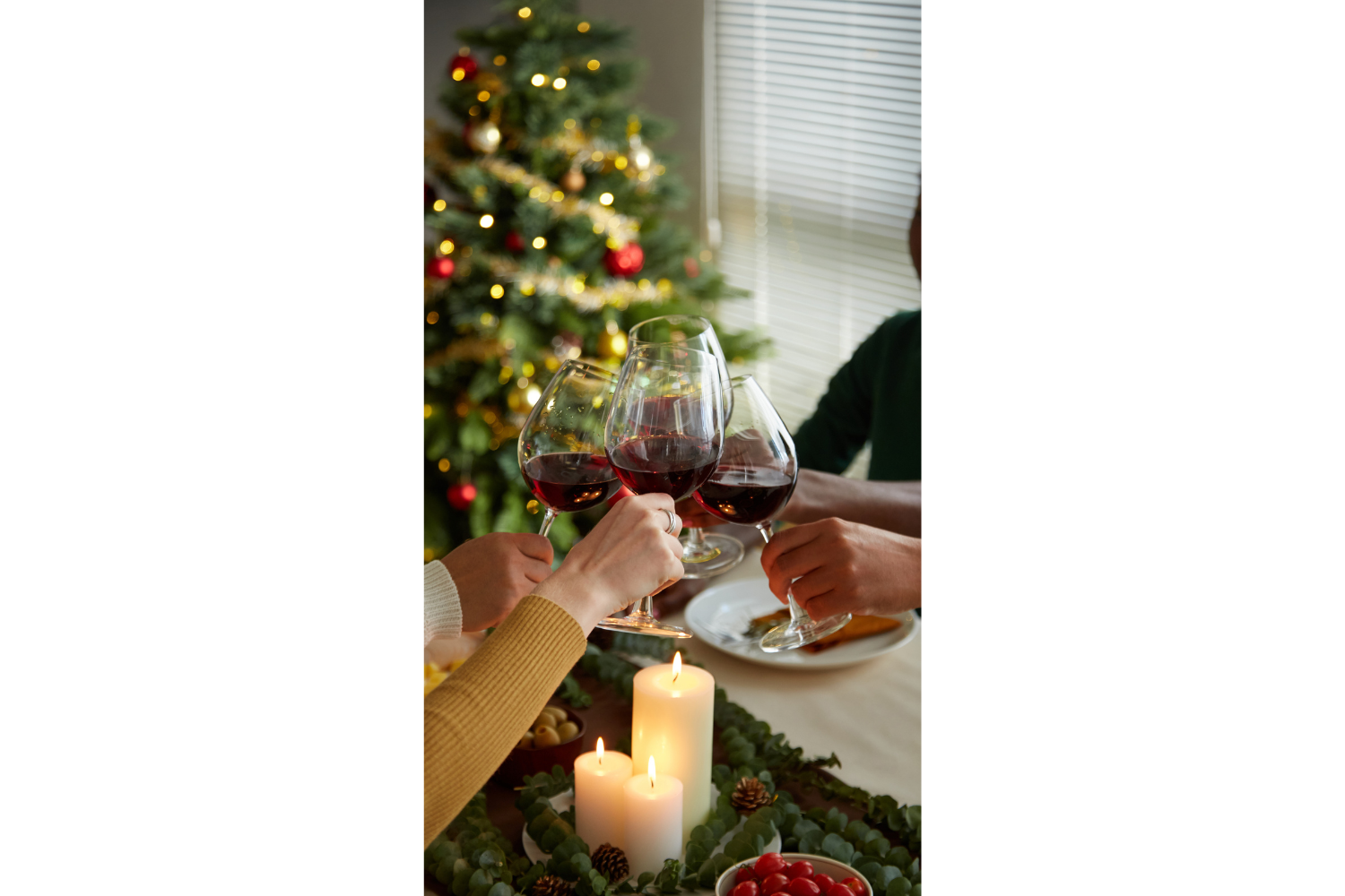 Holiday celebration with friends clinking wine by the Christmas tree
