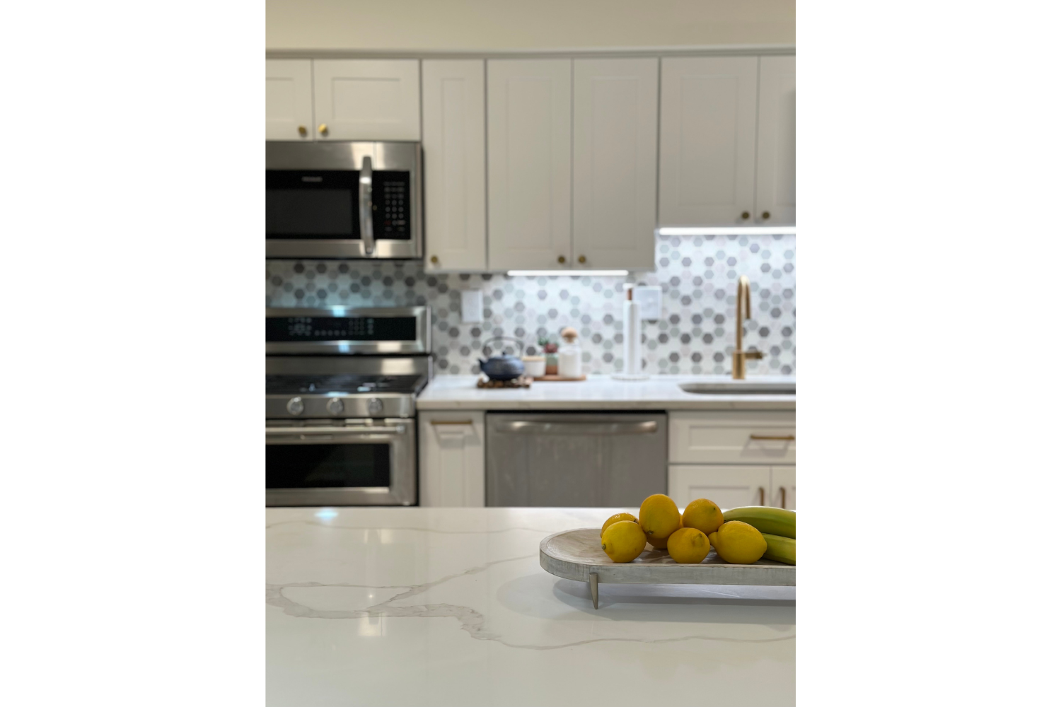Light and airy kitchen styling by House of Shima featuring fresh lemons, layered textures, white cabinetry, warm brass accents, and a bright summer-inspired aesthetic.