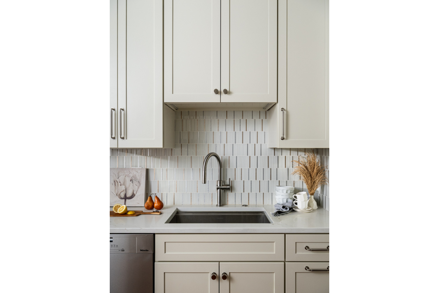 Kitchen detail with custom cabinetry, neutral tile backsplash, and integrated sink area showcasing thoughtful material selection and craftsmanship