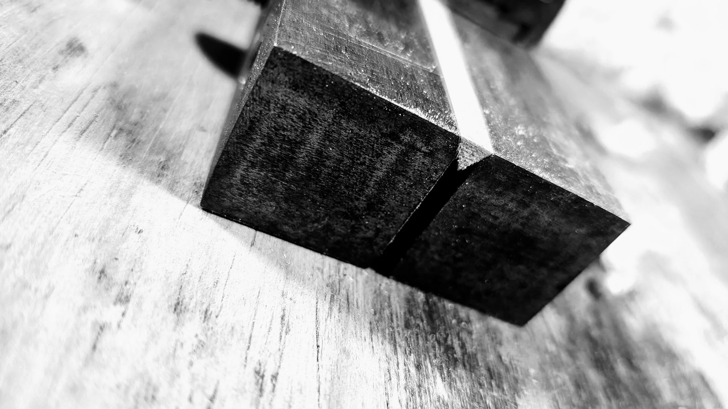 Close-up black-and-white photo of a metal bookend resting on a wooden surface.