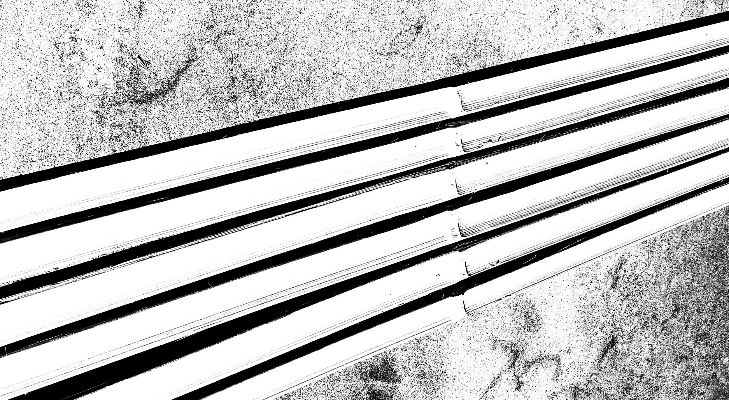 Black and white photo of stacked concrete slabs or tiles on a rough ground surface.