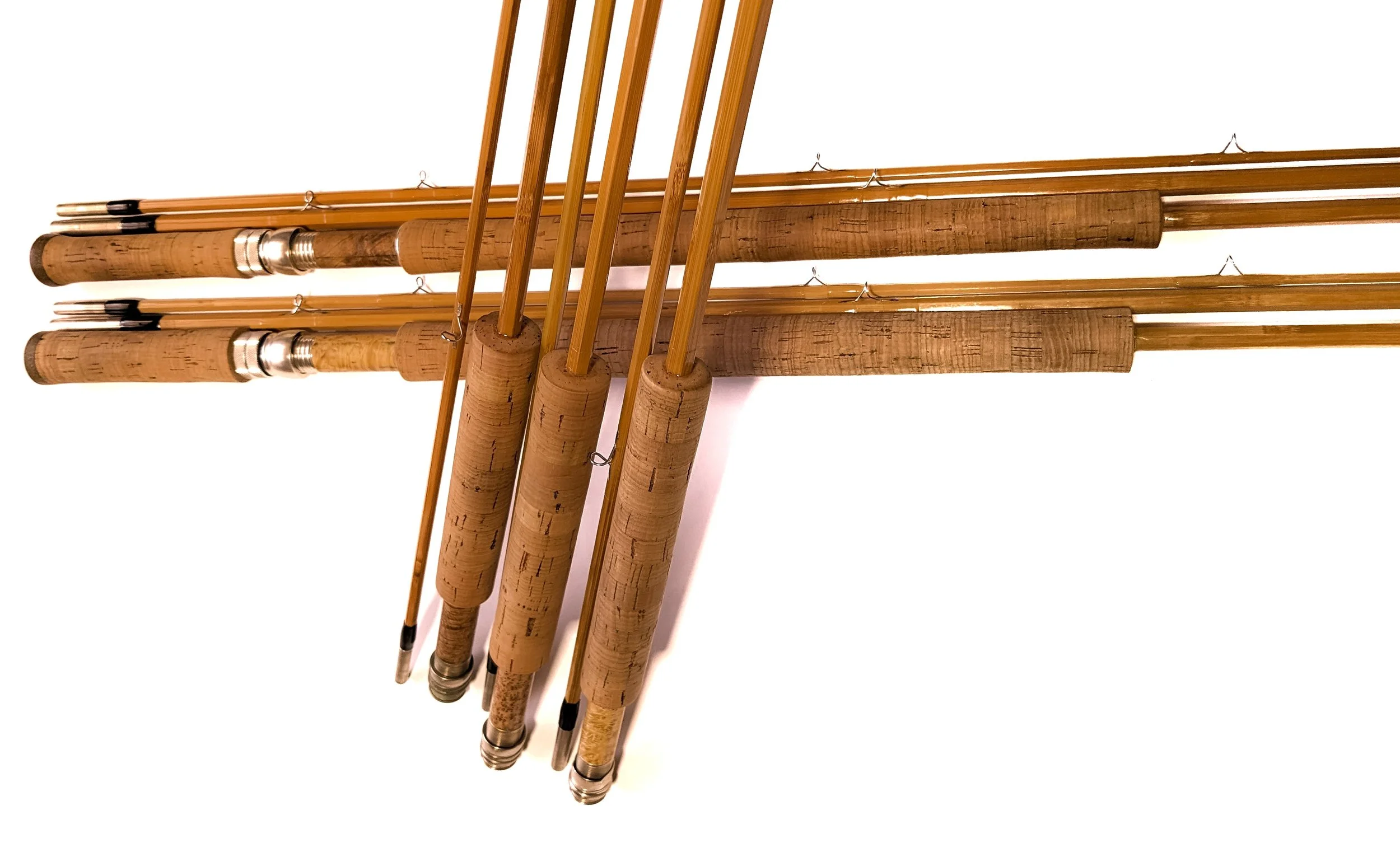 Collection of six bamboo fishing rods with cork handles arranged vertically.