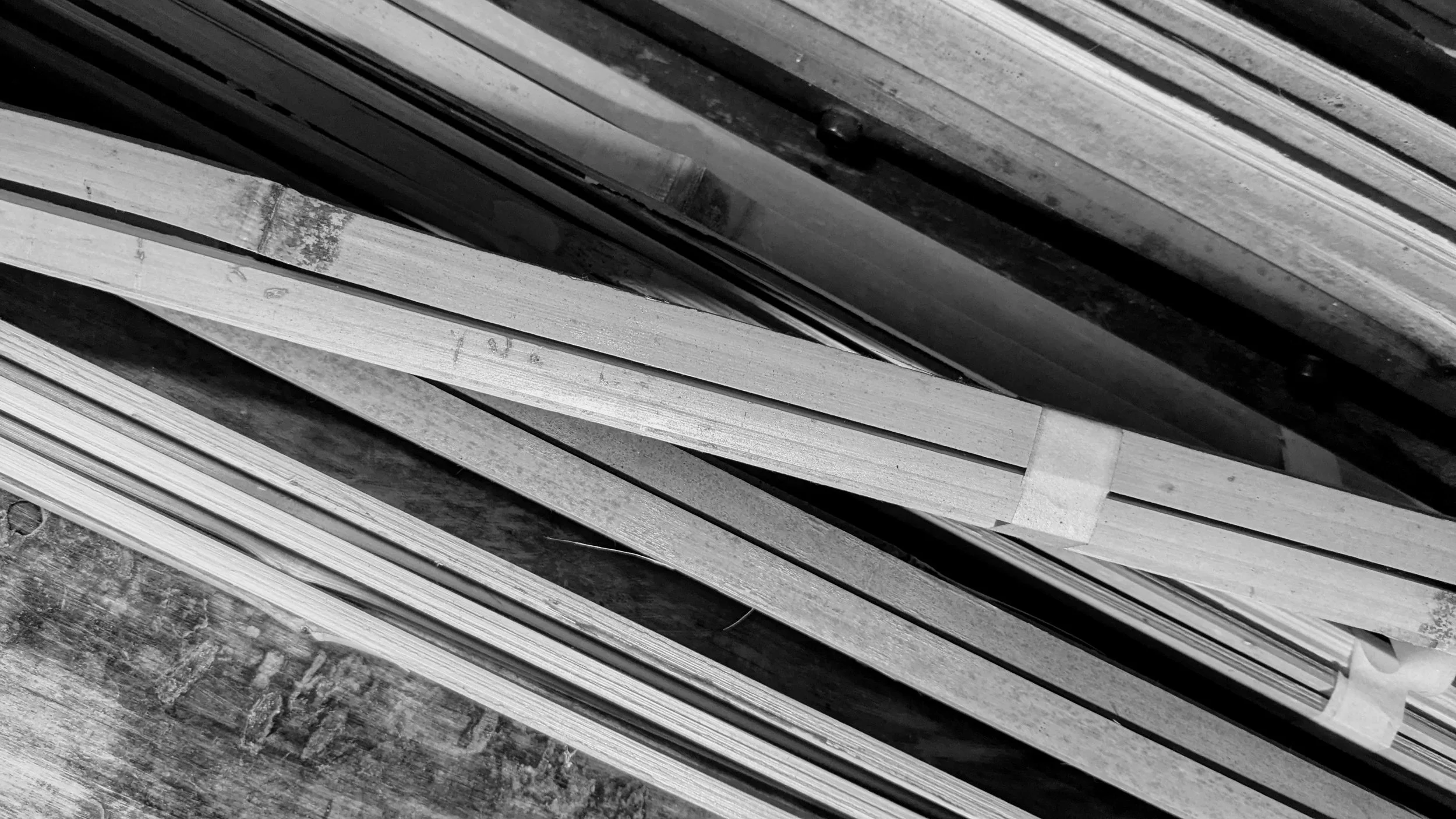 A row of wooden planks stacked vertically on a rough concrete surface.