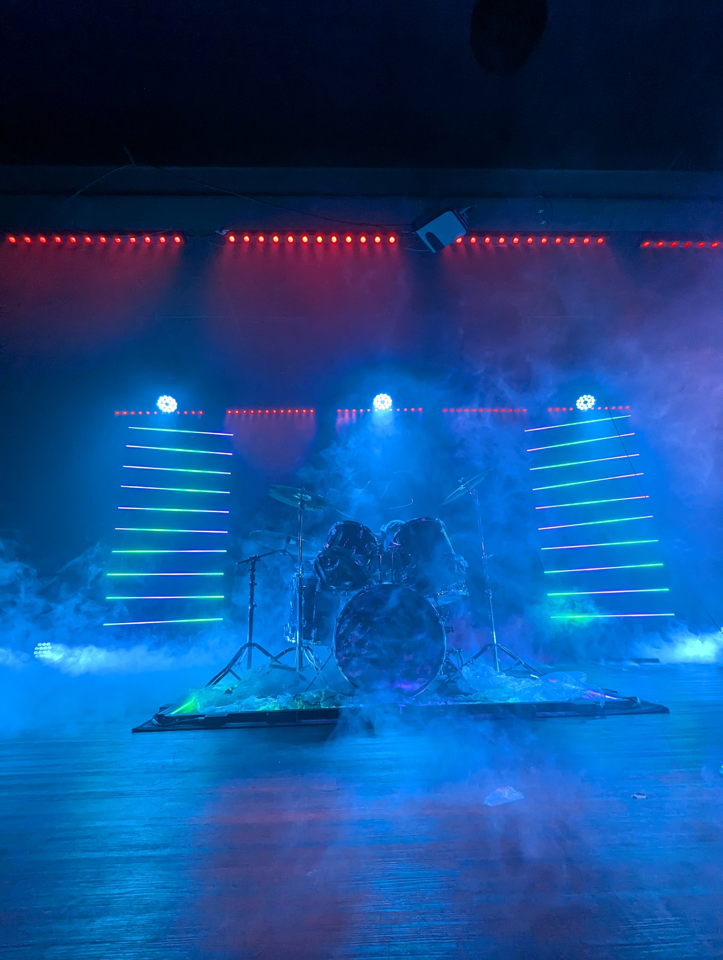 Drum set on stage with colorful lighting and fog effects