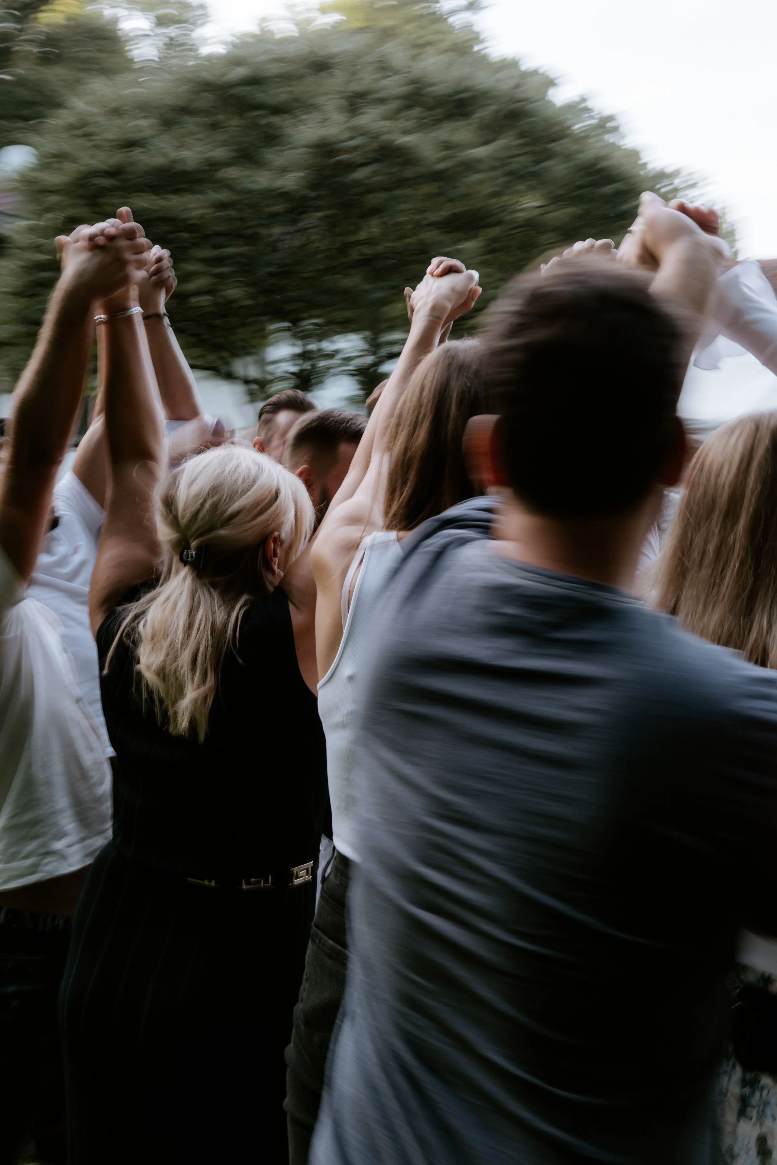 Dav lidí venku zvedá ruce a tančí. drží se za ruce, slaví. Svatební
