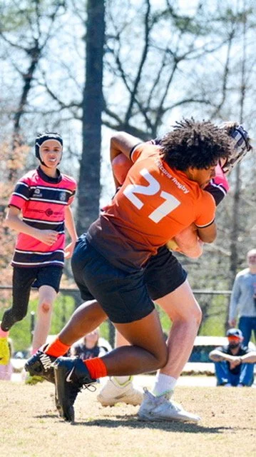 Highschool boy playing rugby makes a safe tackle using correct technique to take down his opponent.