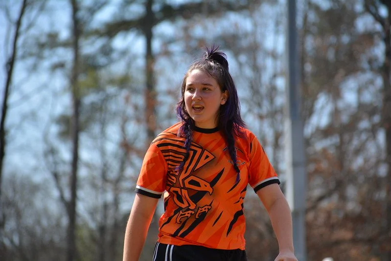 Confident high school girl walks on the pitch ready to play rugby.