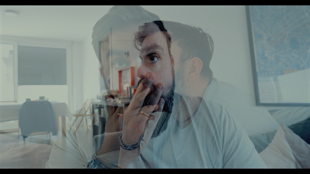 Double-exposure portrait of a bearded man smoking indoors in a bright apartment